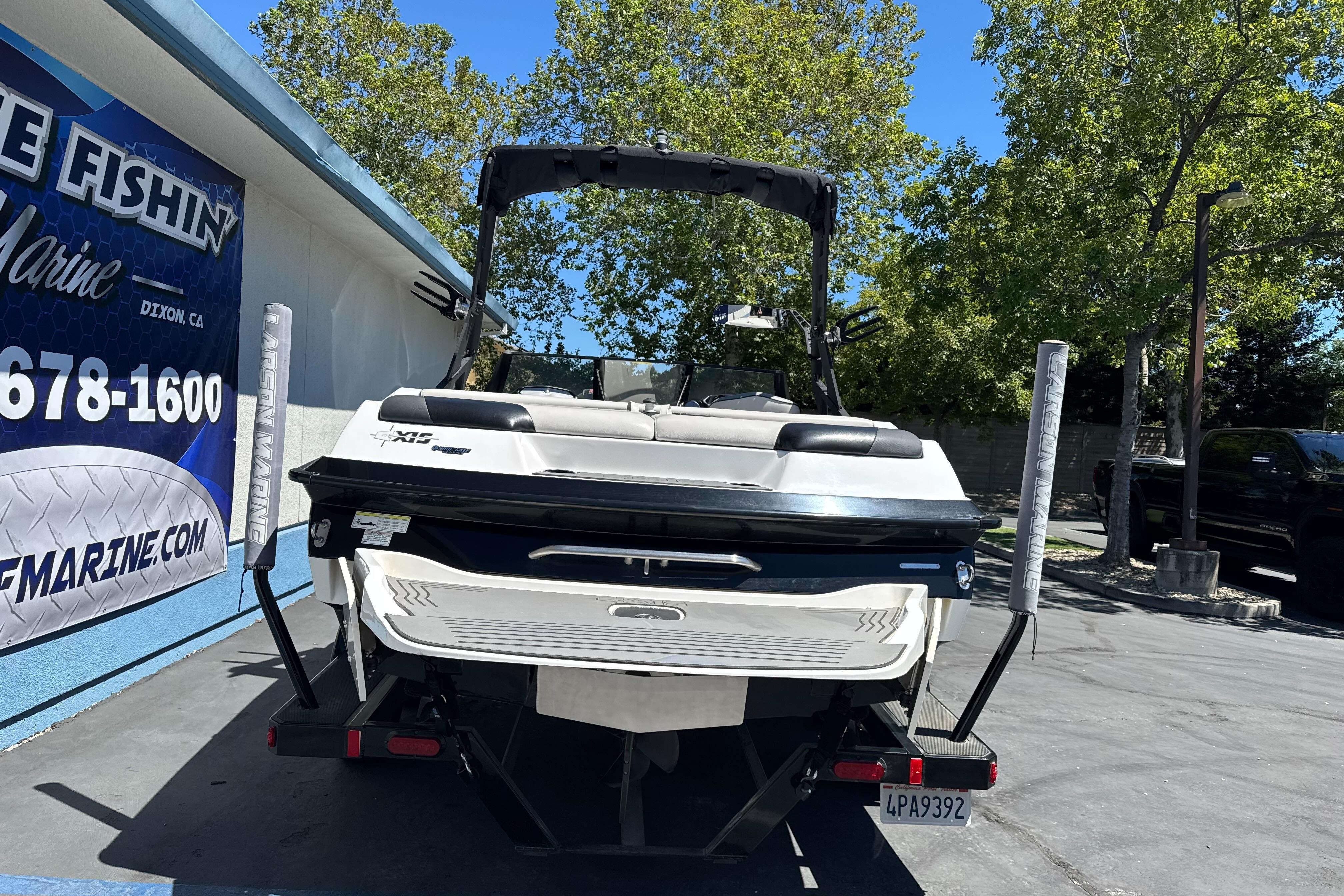 2015 Axis A20 boat on trailer at dealership, surrounded by trees and signage.