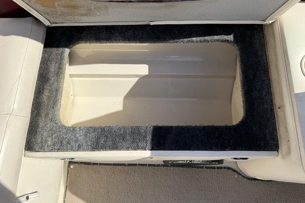 Storage compartment in a 1999 Glastron GT 225 boat, featuring a carpeted interior.
