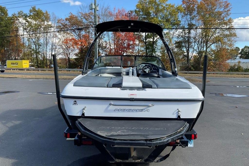 2015 Moomba Outback V boat, rear view, parked outdoors with autumn trees in background.