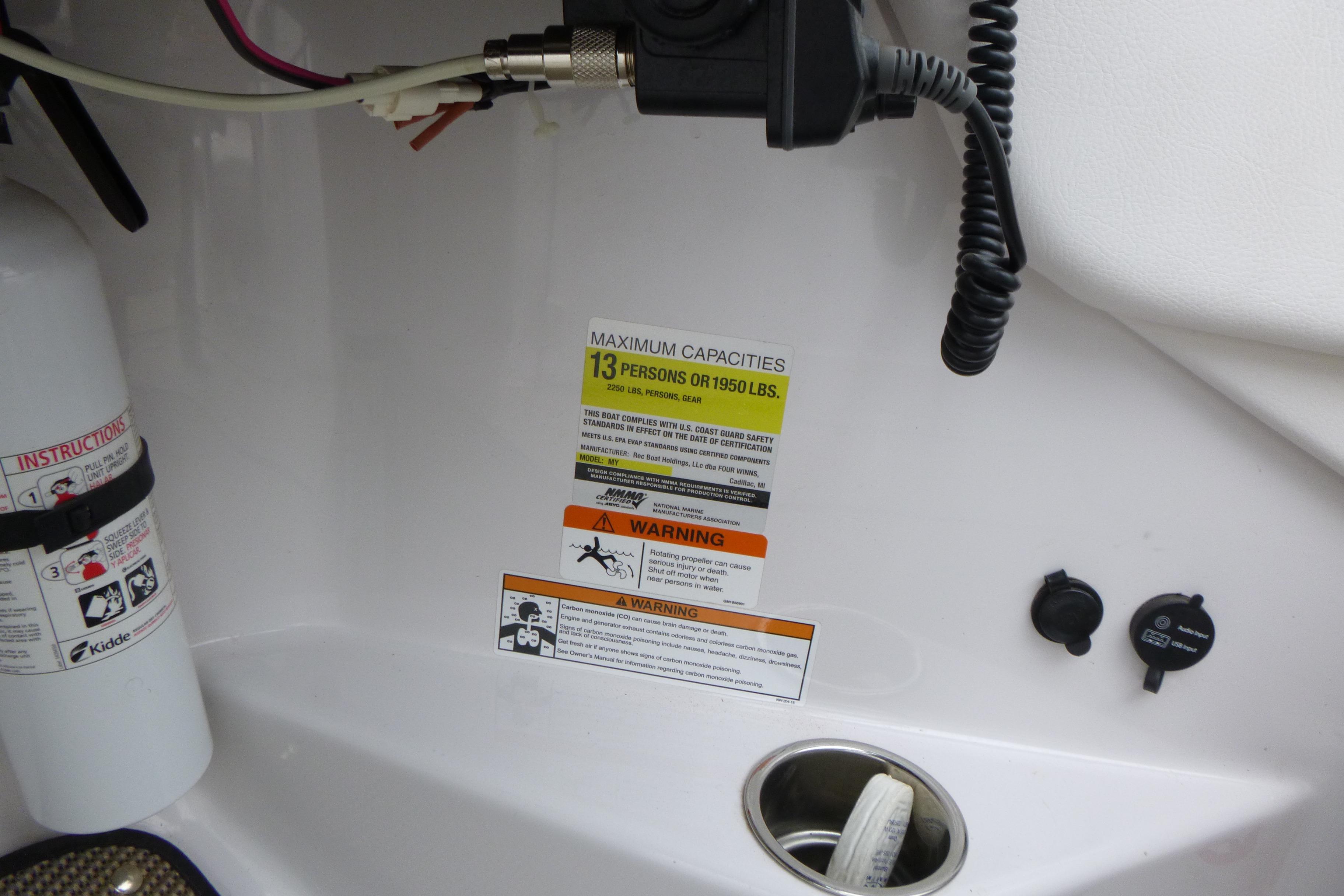 2017 Four Winns H260 boat capacity label, fire extinguisher, and warning signs.