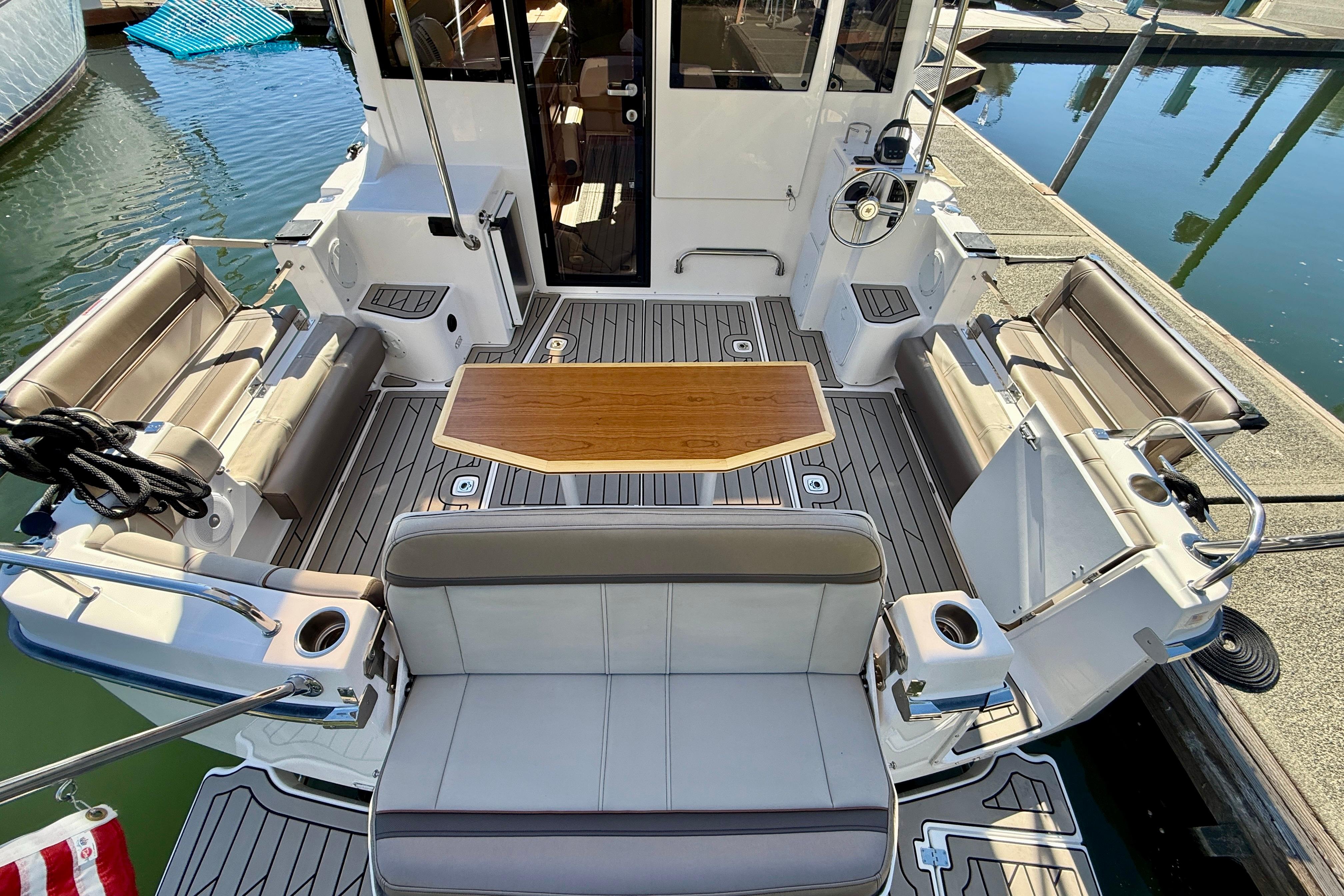 2023 Cutwater C-30 Sedan boat interior with seating and wooden table at dock.