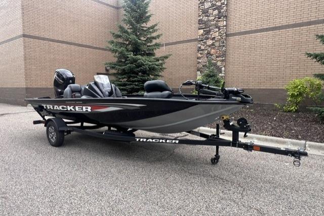 2026 Tracker Pro Team 175 boat on trailer, parked outdoors near brick wall.