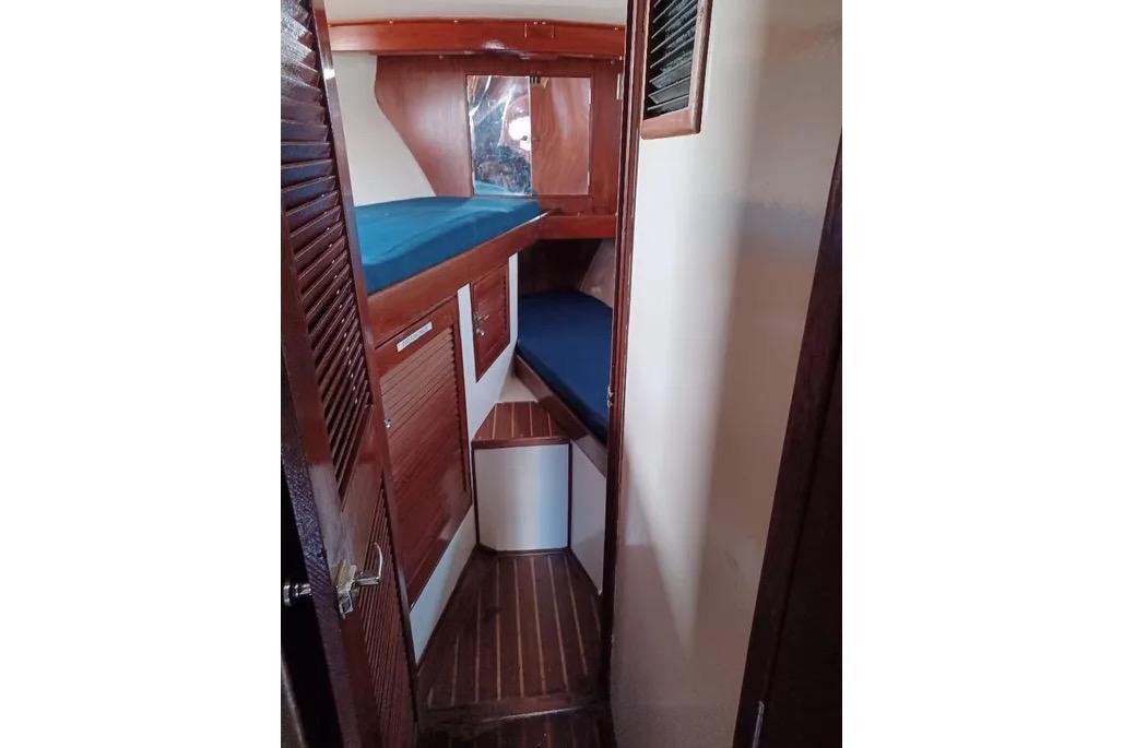 1977 Morgan Out Island 51 yacht interior with wooden paneling and blue bedding.