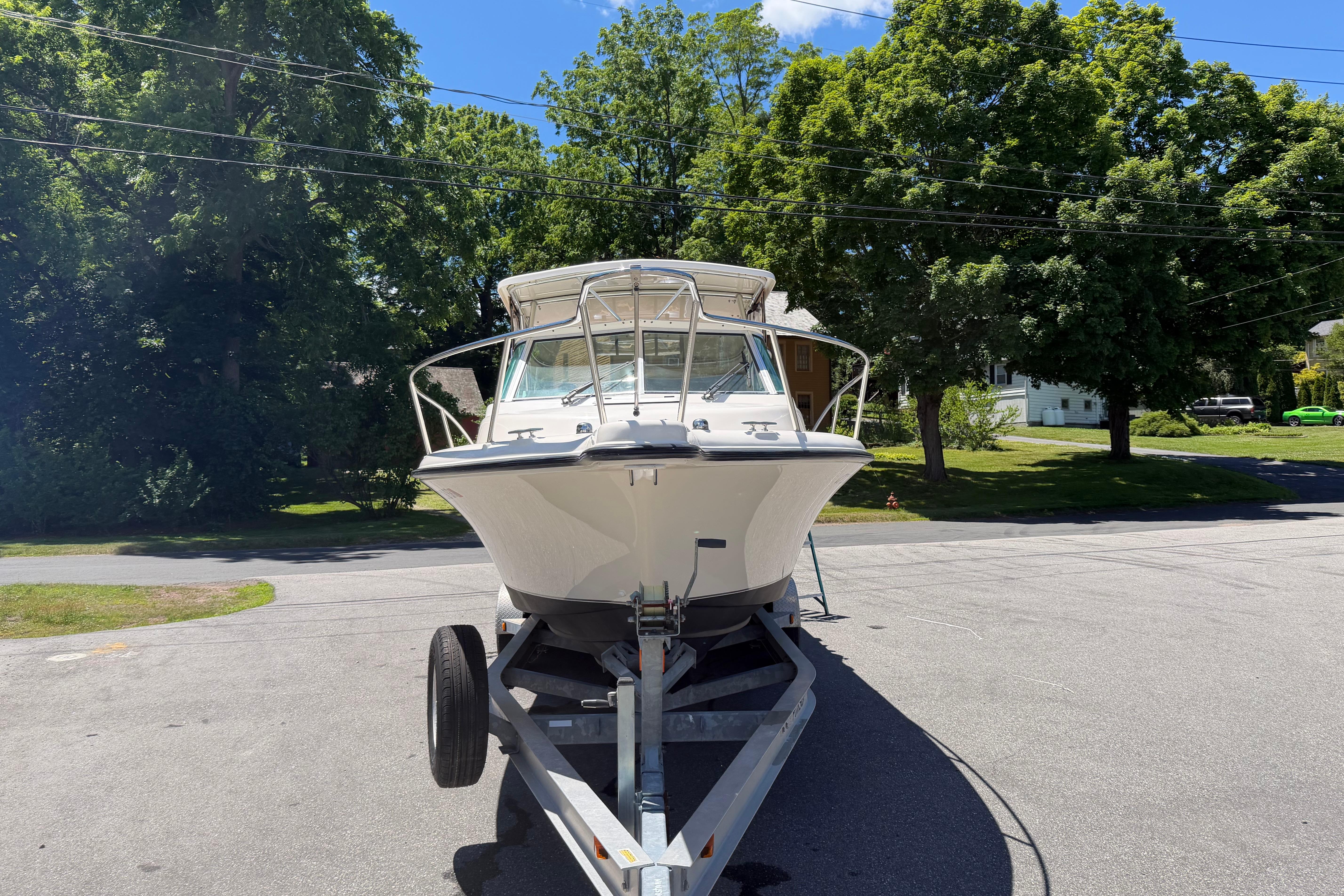 2010 Pursuit OS 255 Offshore boat on trailer, parked on a sunny street.