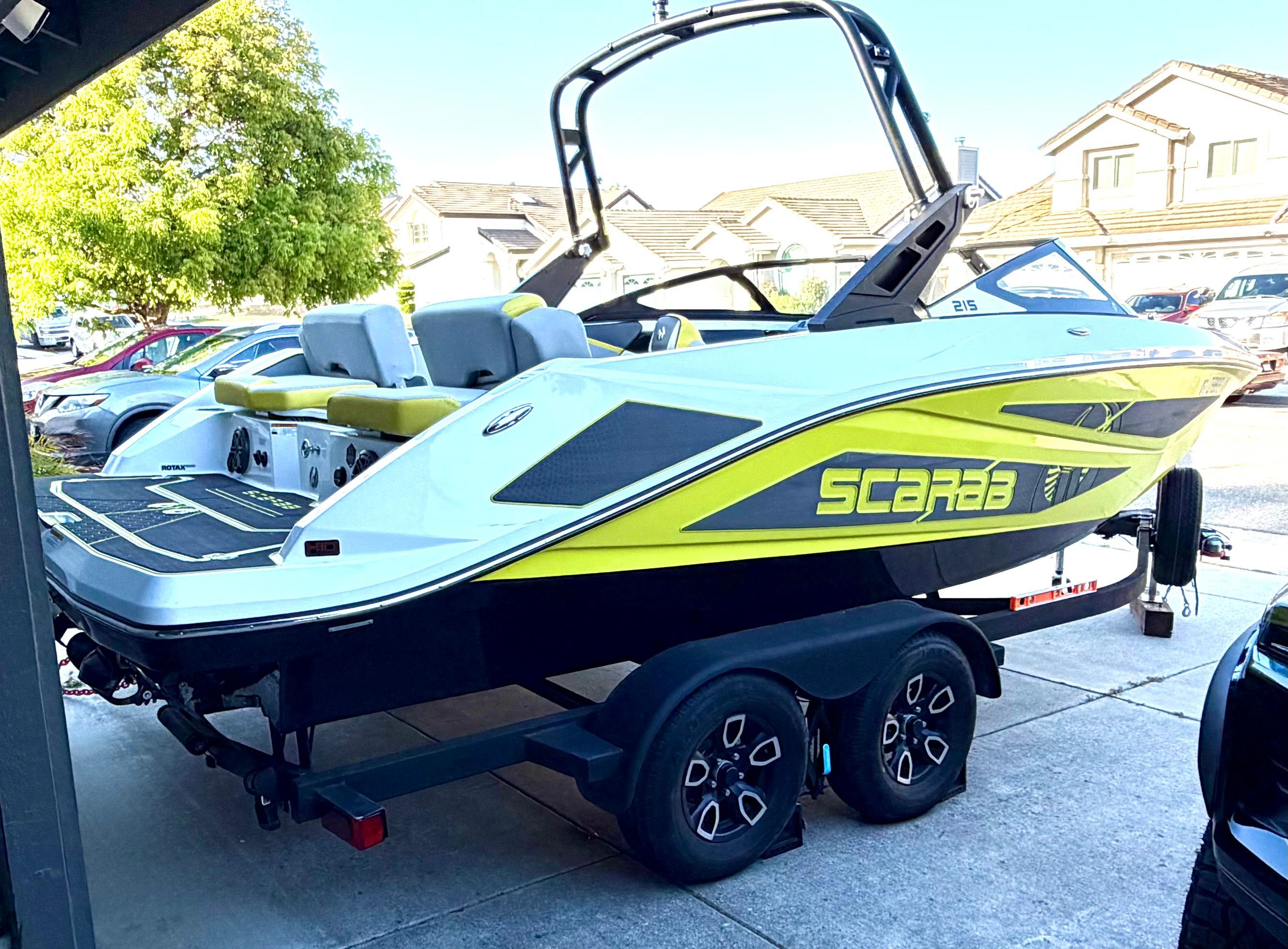 A 2023 Scarab 215 ID boat parked on a trailer in a residential area.
