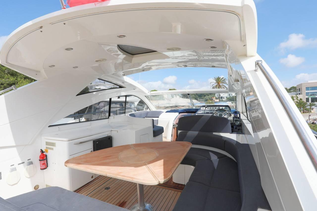 Luxurious 2006 Fairline Targa 47 yacht interior with seating and table under a sunny sky.
