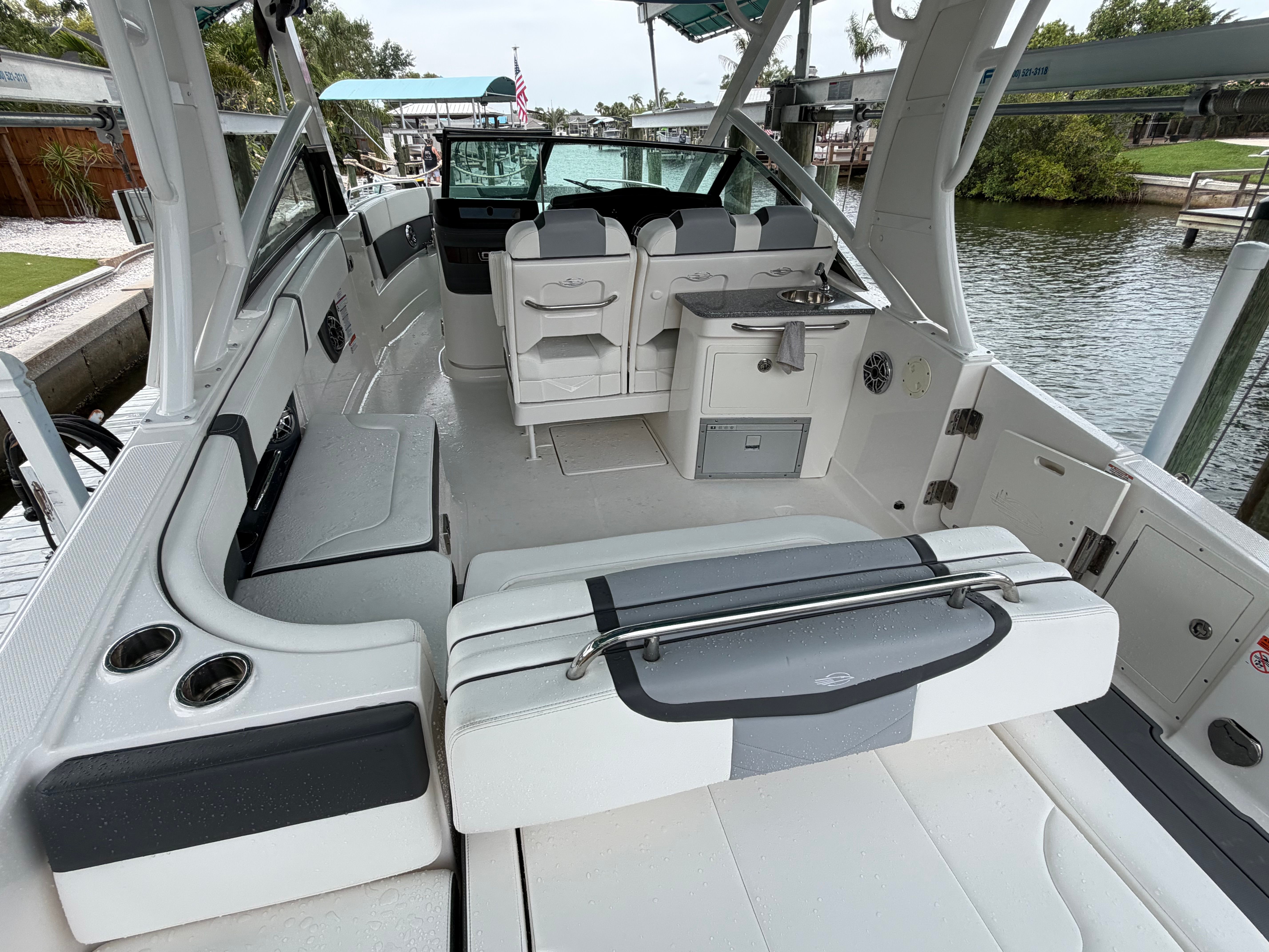 A modern boat with stylish seating and open deck, docked by a calm canal.