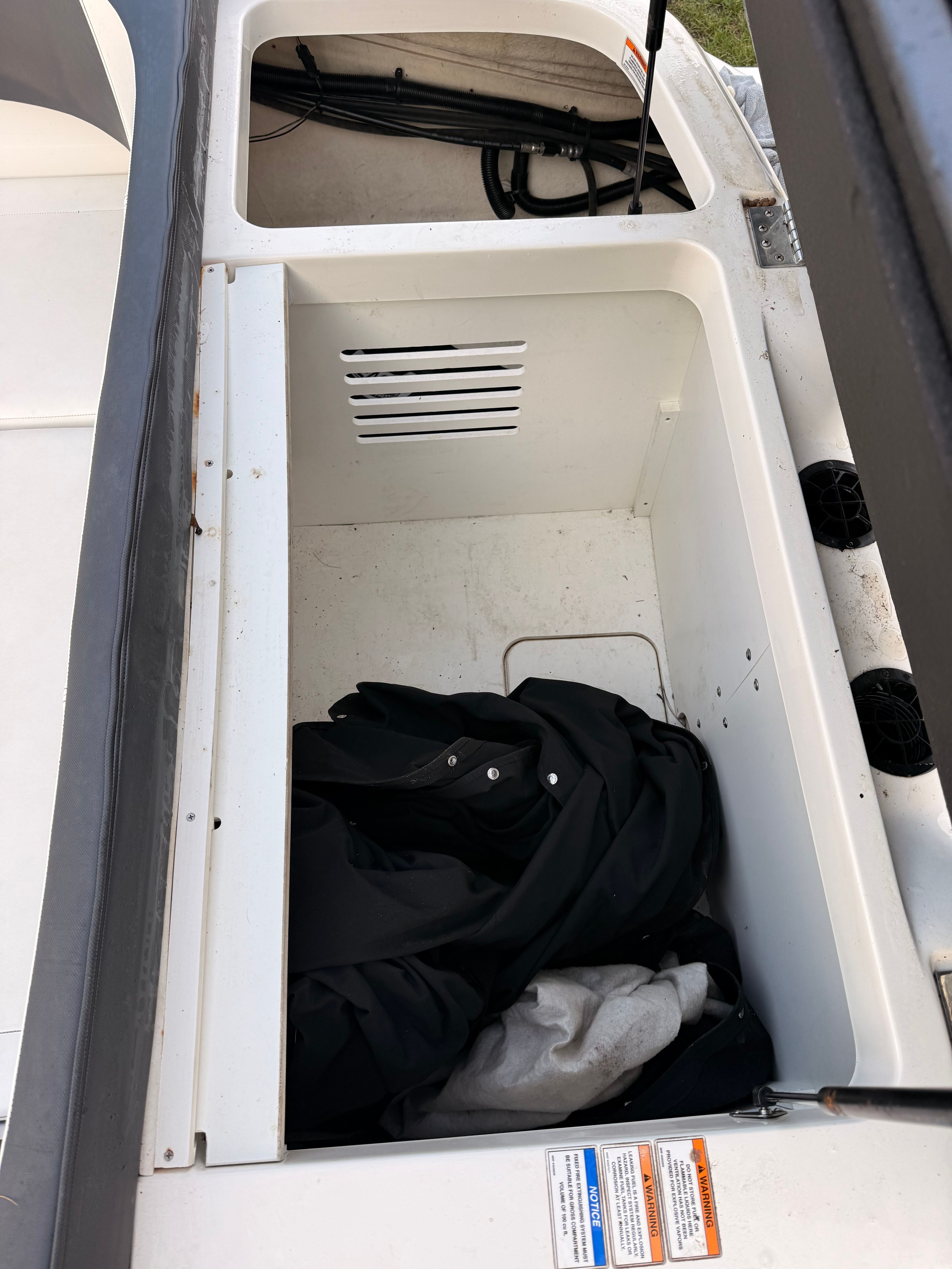 An open storage compartment on a Sea Ray SPX 210 Outboard boat, partially filled with clothing.