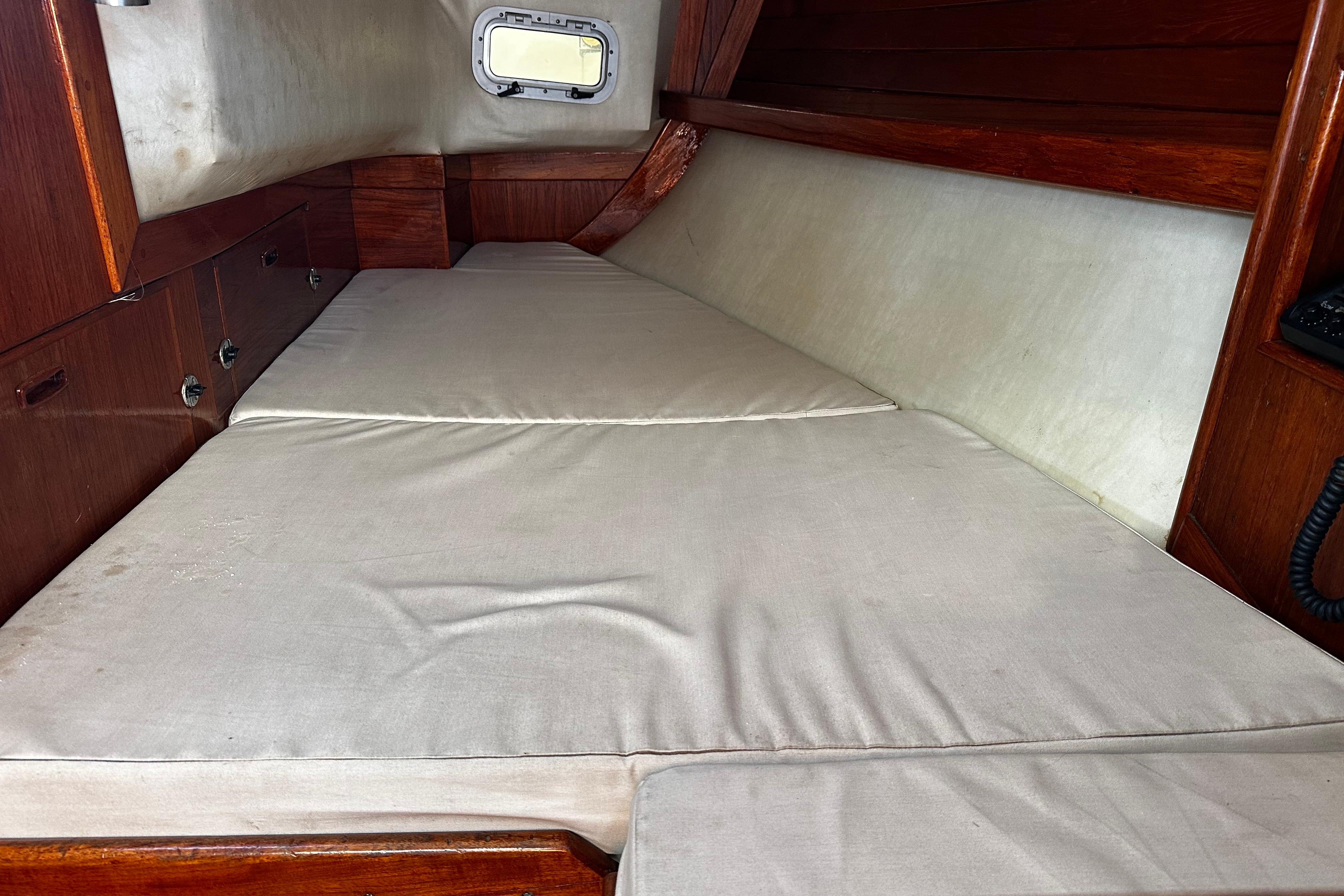 Interior cabin of 1986 Ericson 381 sailboat with cushioned berth and wooden paneling.