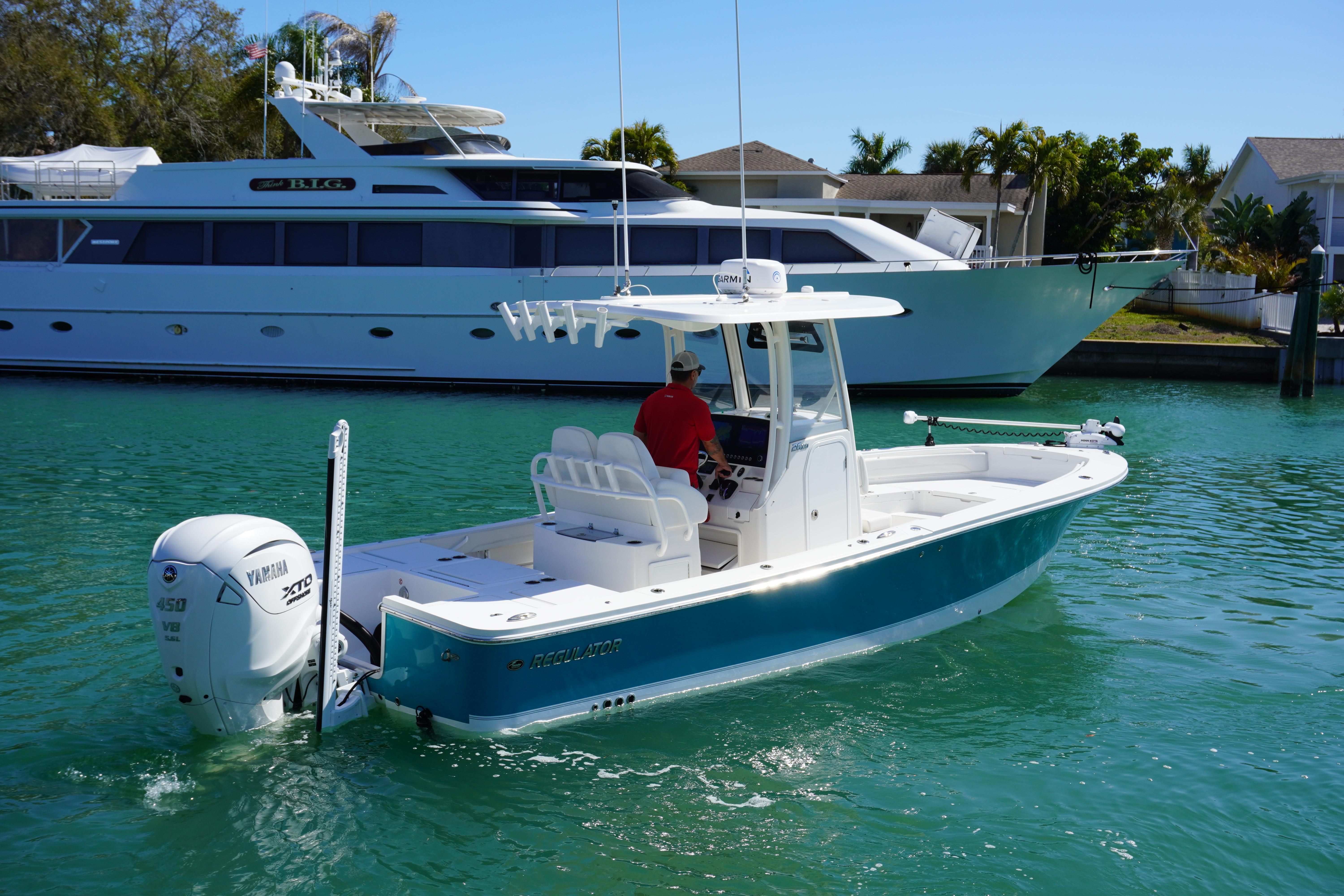 2024 Regulator 26XO boat cruising in clear turquoise water near a large yacht.