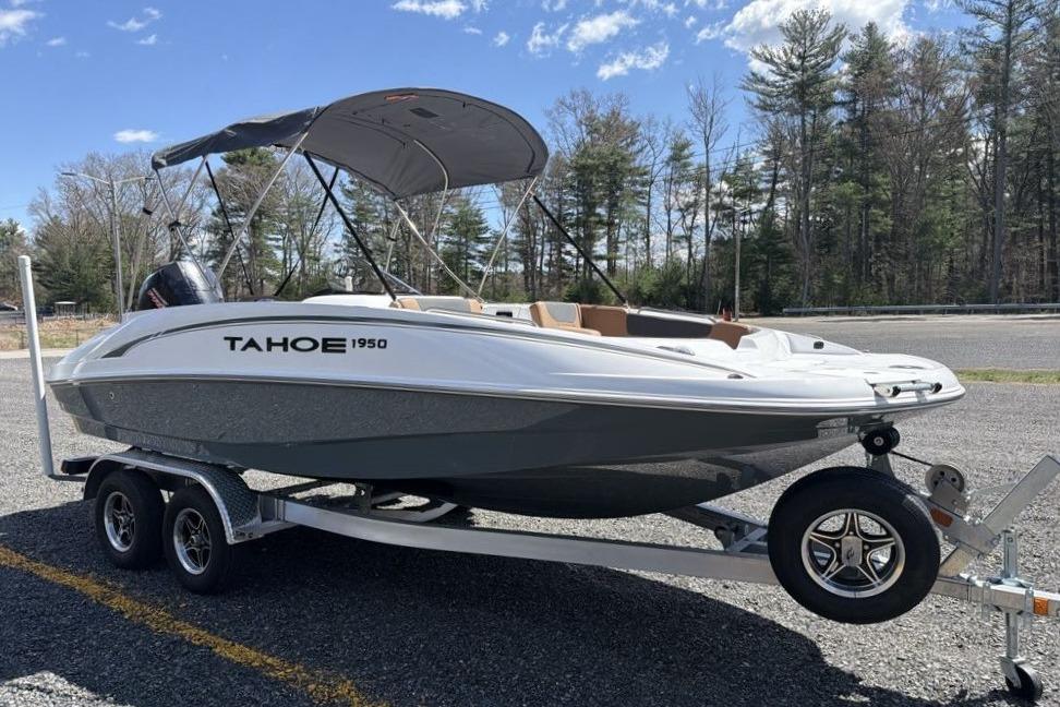 2026 Tahoe 1950 boat on trailer, parked outdoors with trees in background.
