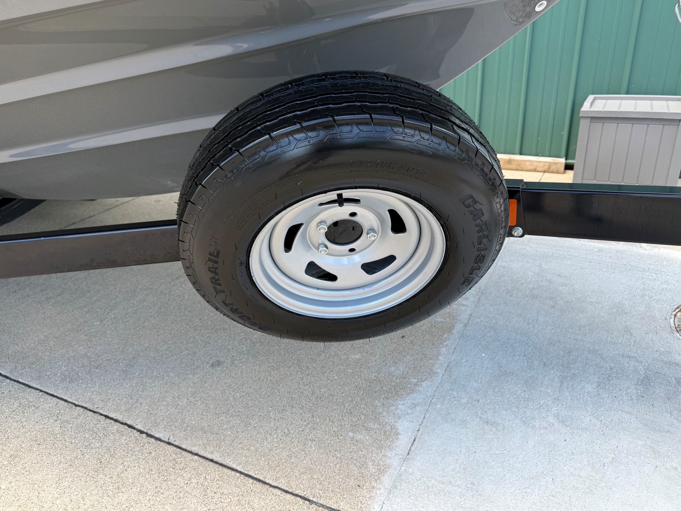 A boat trailer with a tire on concrete ground.