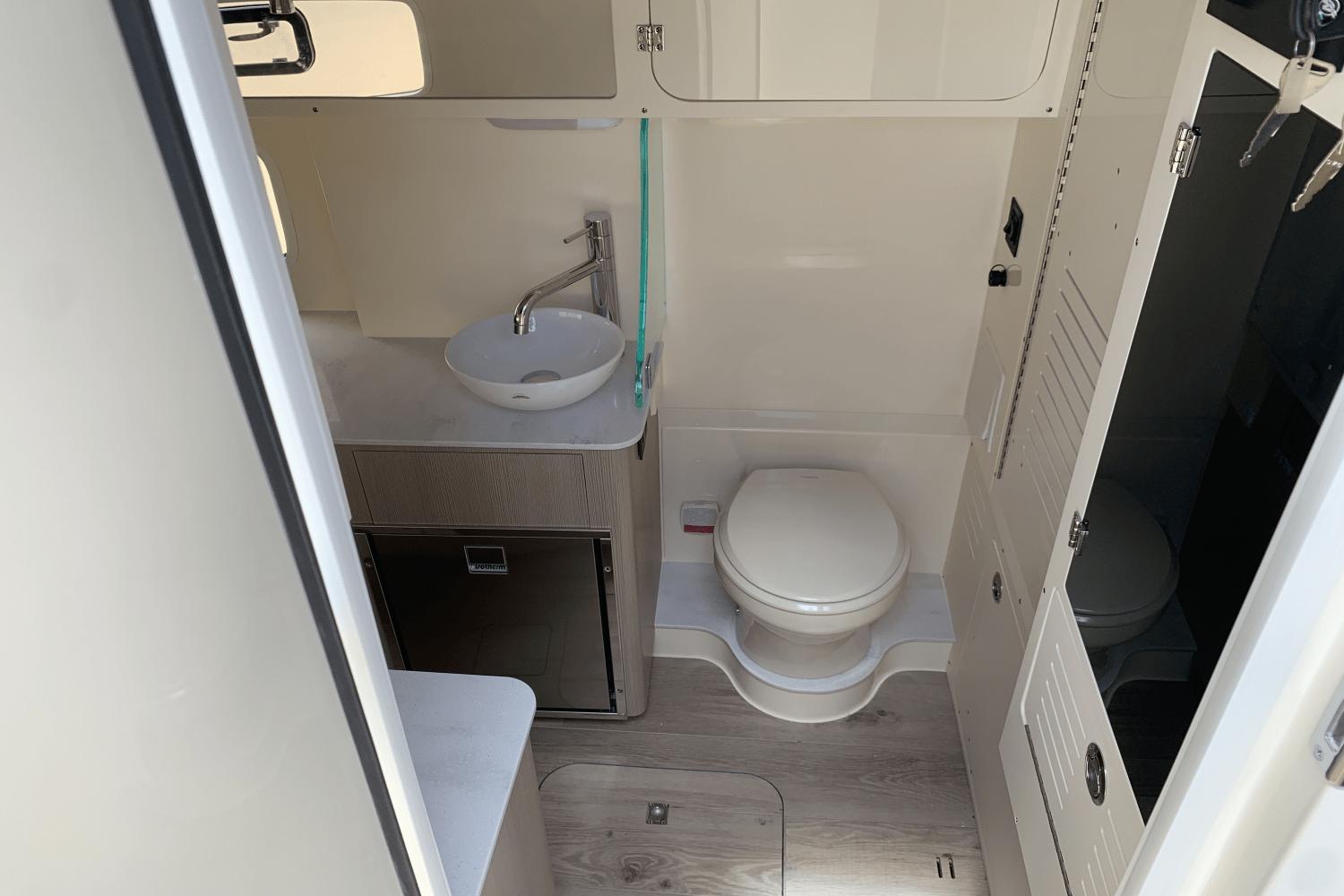 2024 Scout 357LXF boat bathroom with sink, toilet, and storage cabinets.