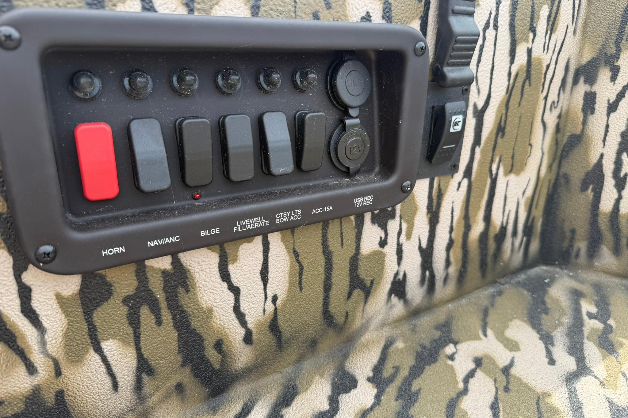 Control panel of 2026 Avid 16 Commander boat with camouflage design and labeled switches.