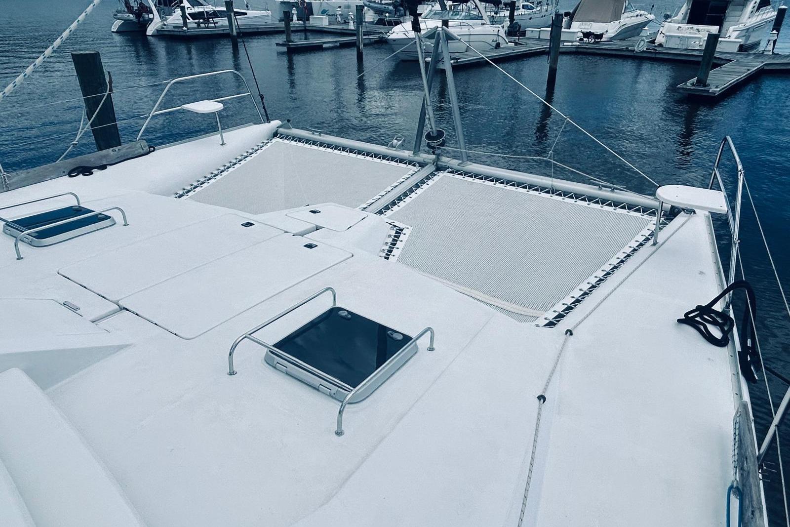2001 Robertson & Caine Leopard catamaran docked at marina, featuring spacious deck and netting.