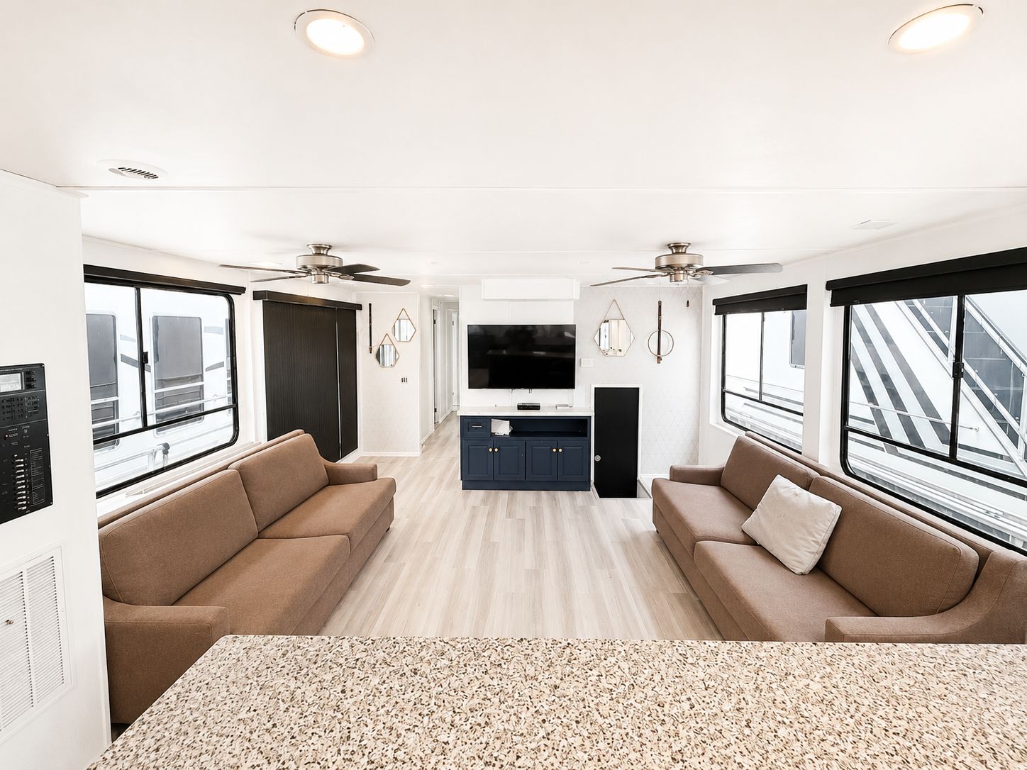 Interior of a modern houseboat with sofas and a TV.