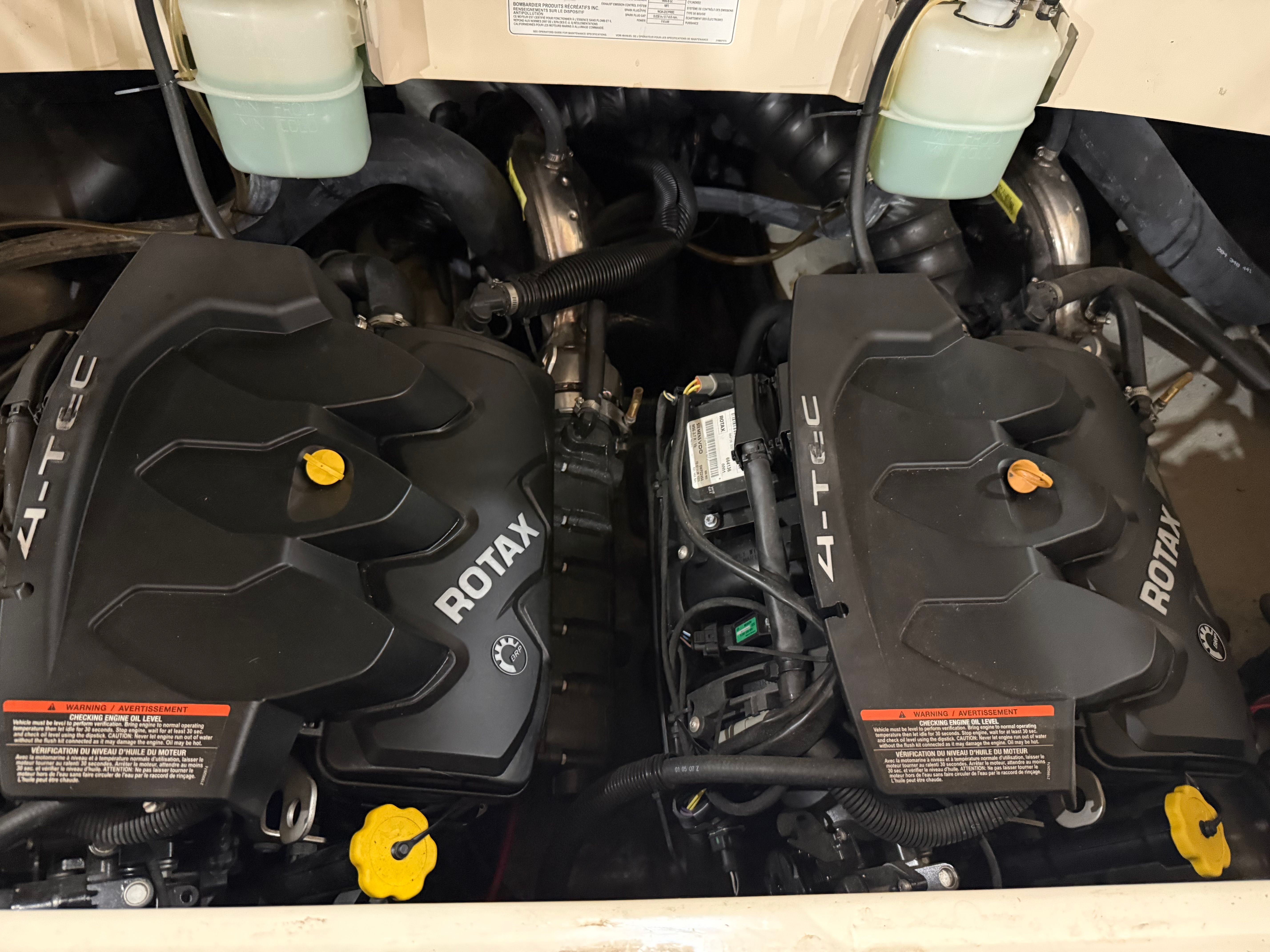 Two Rotax engines in a boat engine compartment, with hoses and fluid reservoirs.