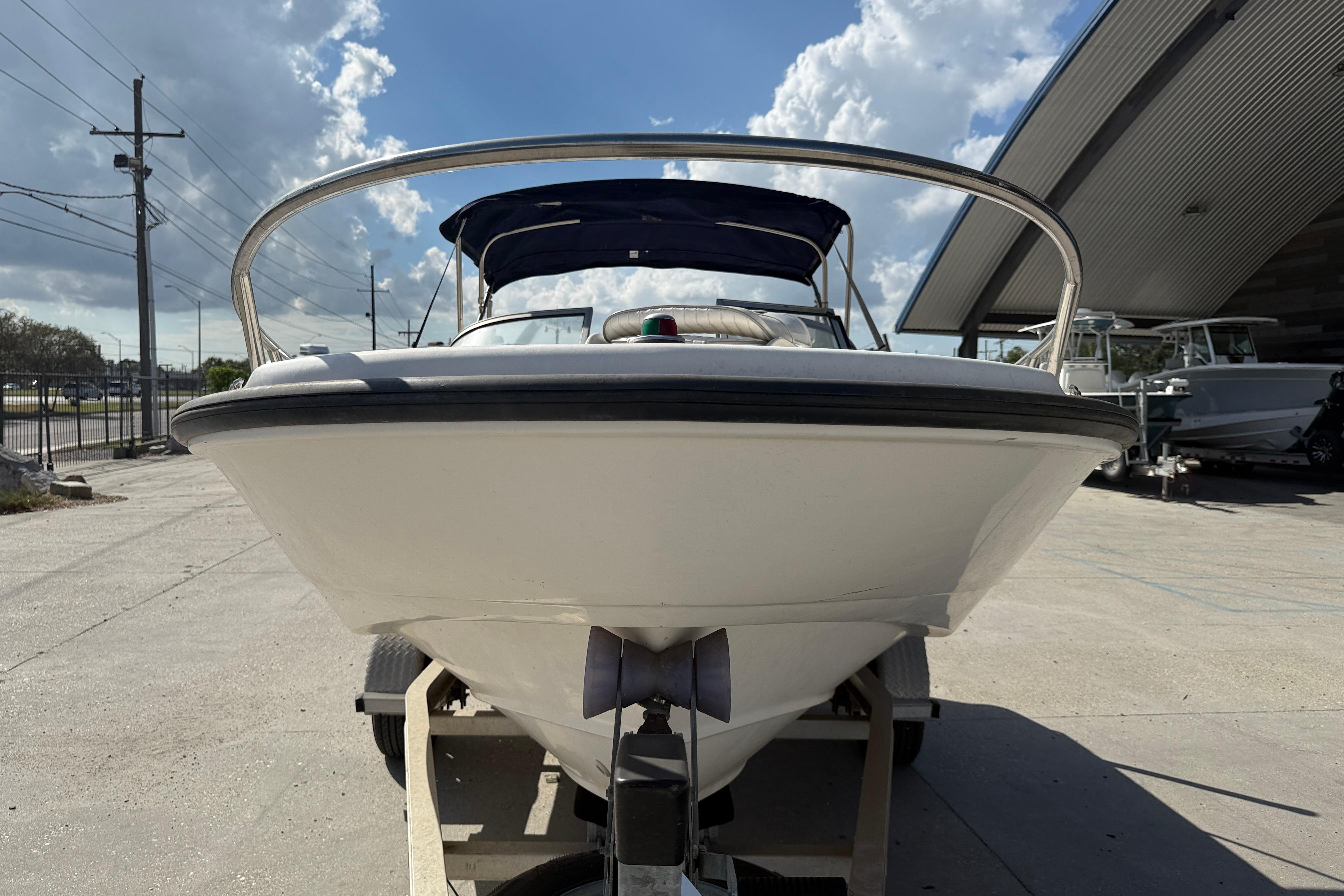 2002 Boston Whaler Ventura 160 boat on trailer, under a partly cloudy sky.