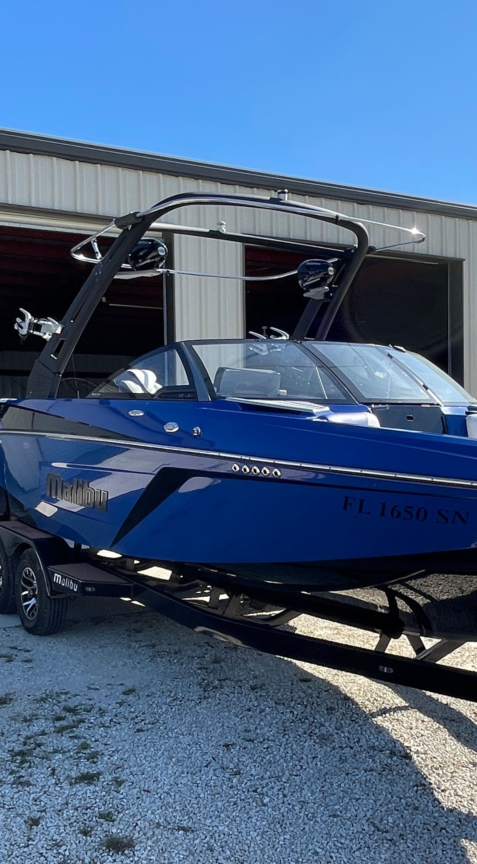 A blue 2019 Malibu Wakesetter 22 LSV on a trailer in front of a warehouse.