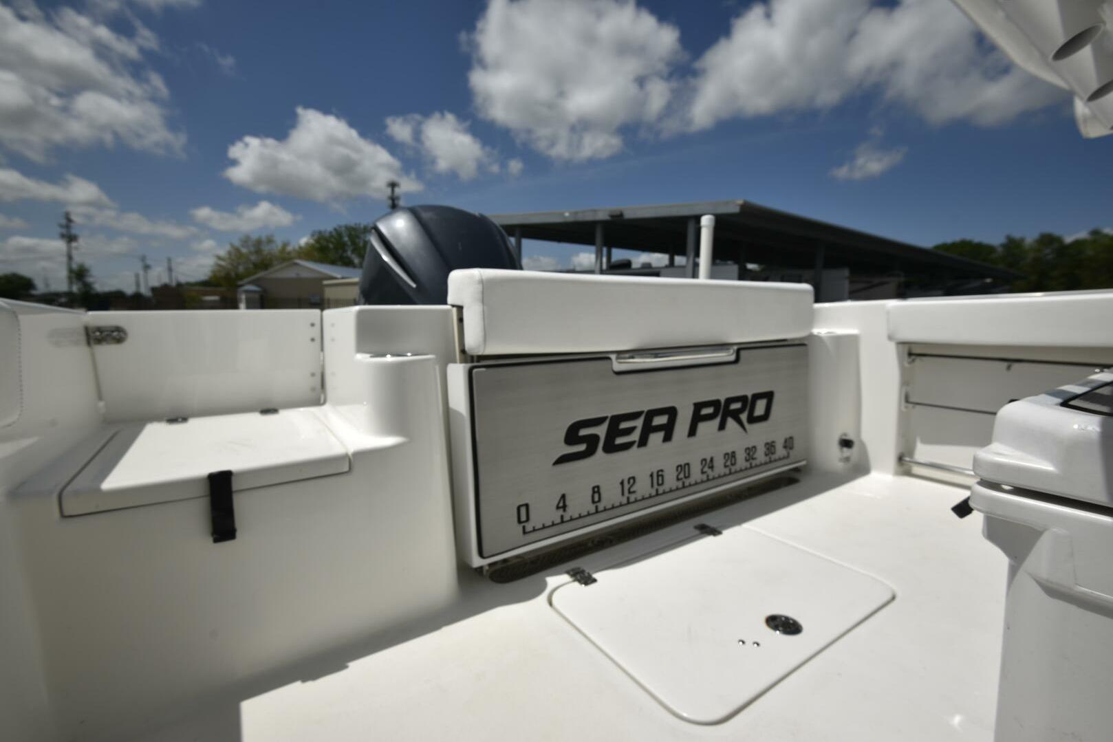 2023 Sea Pro 239 Deep V CC boat interior with seating and storage under a blue sky.