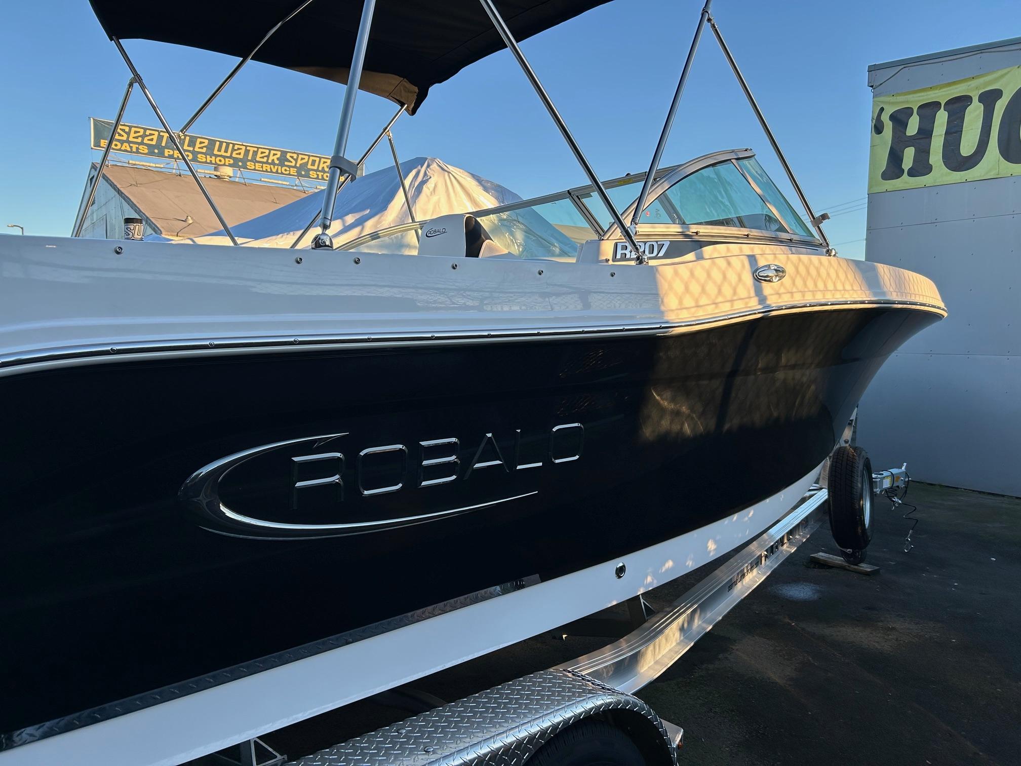 2026 Robalo R207 Dual Console boat on trailer, side view, under clear blue sky.