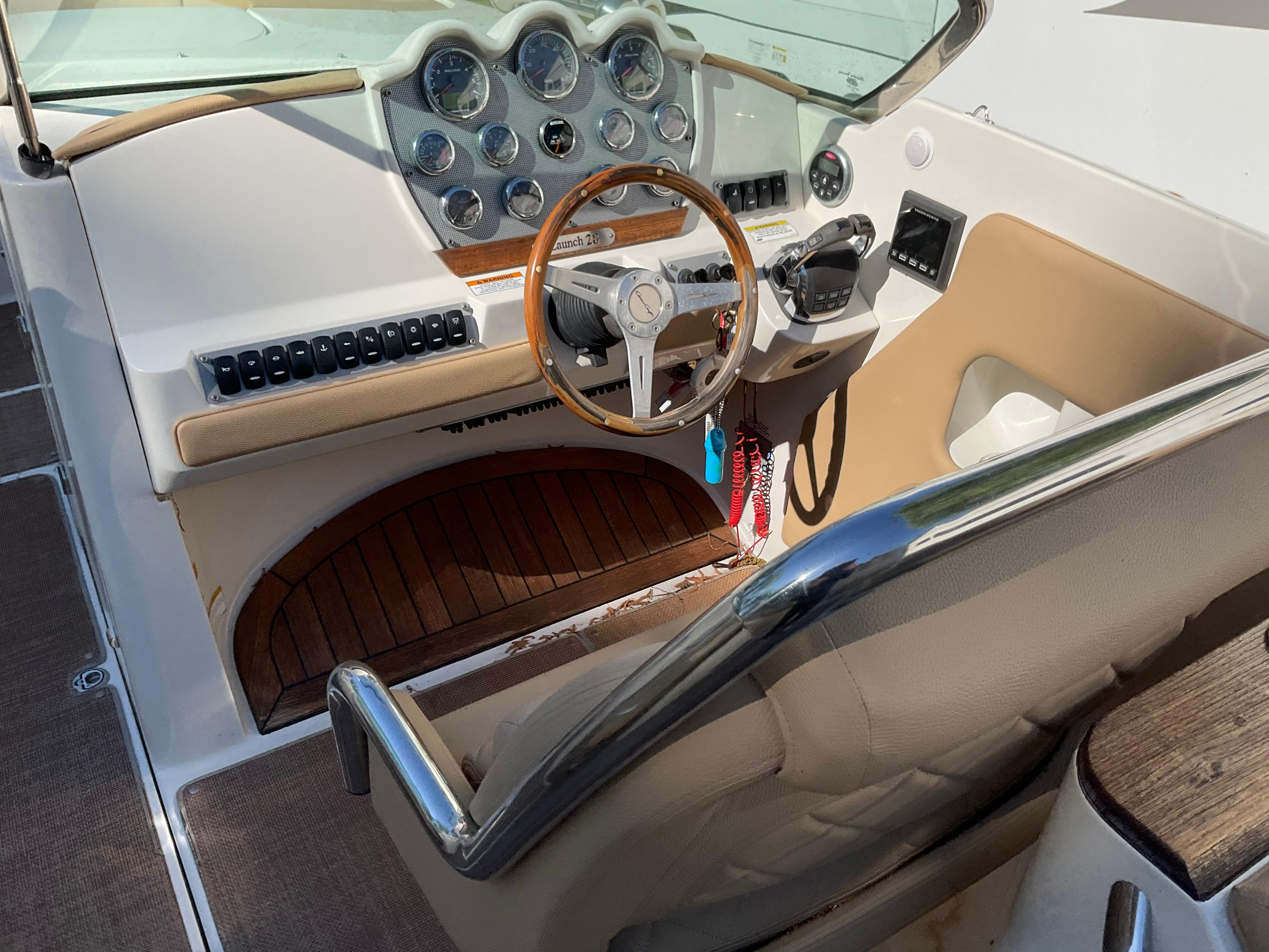 2014 Chris-Craft Launch 28 boat cockpit with wooden steering wheel and dashboard controls.