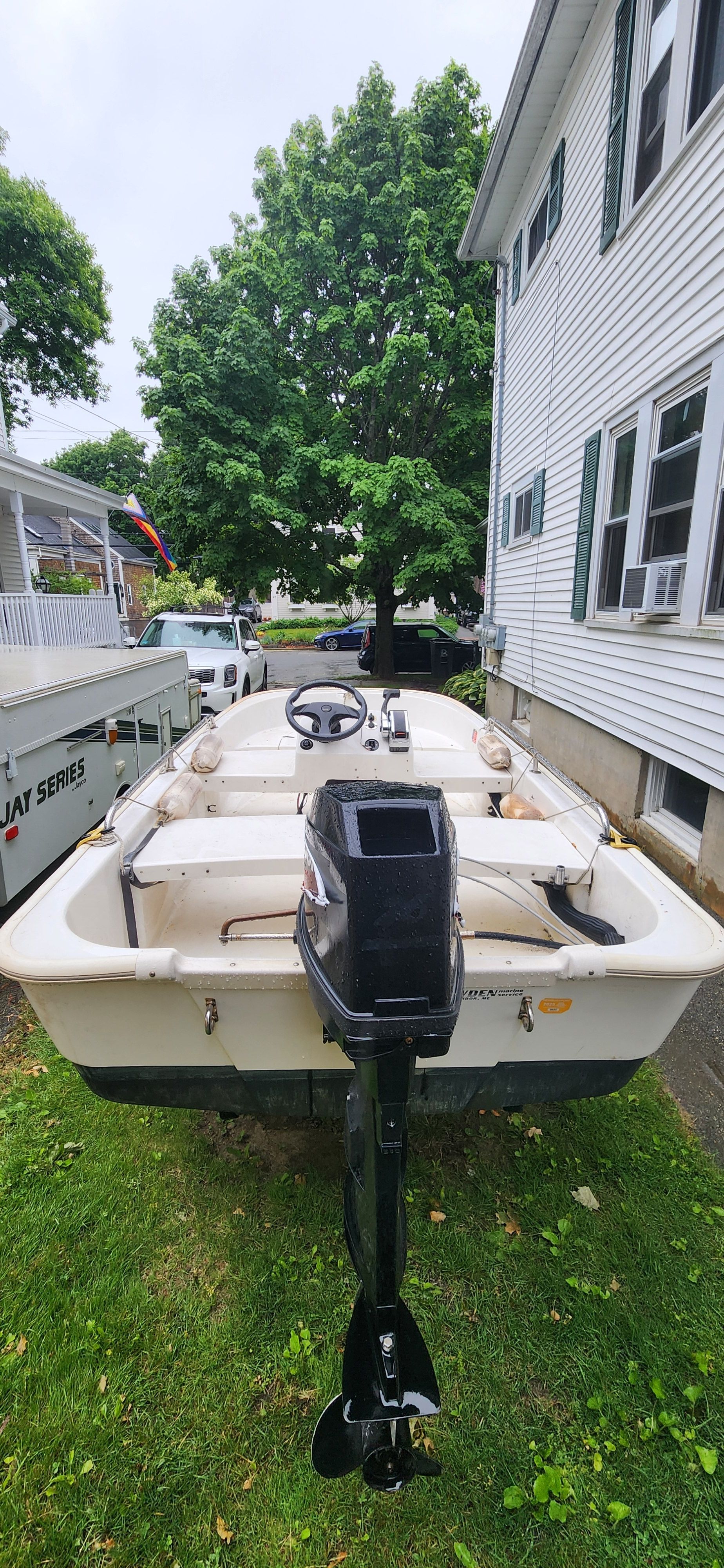 A Boston Whaler 110 Sport boat is on a lawn next to a house.