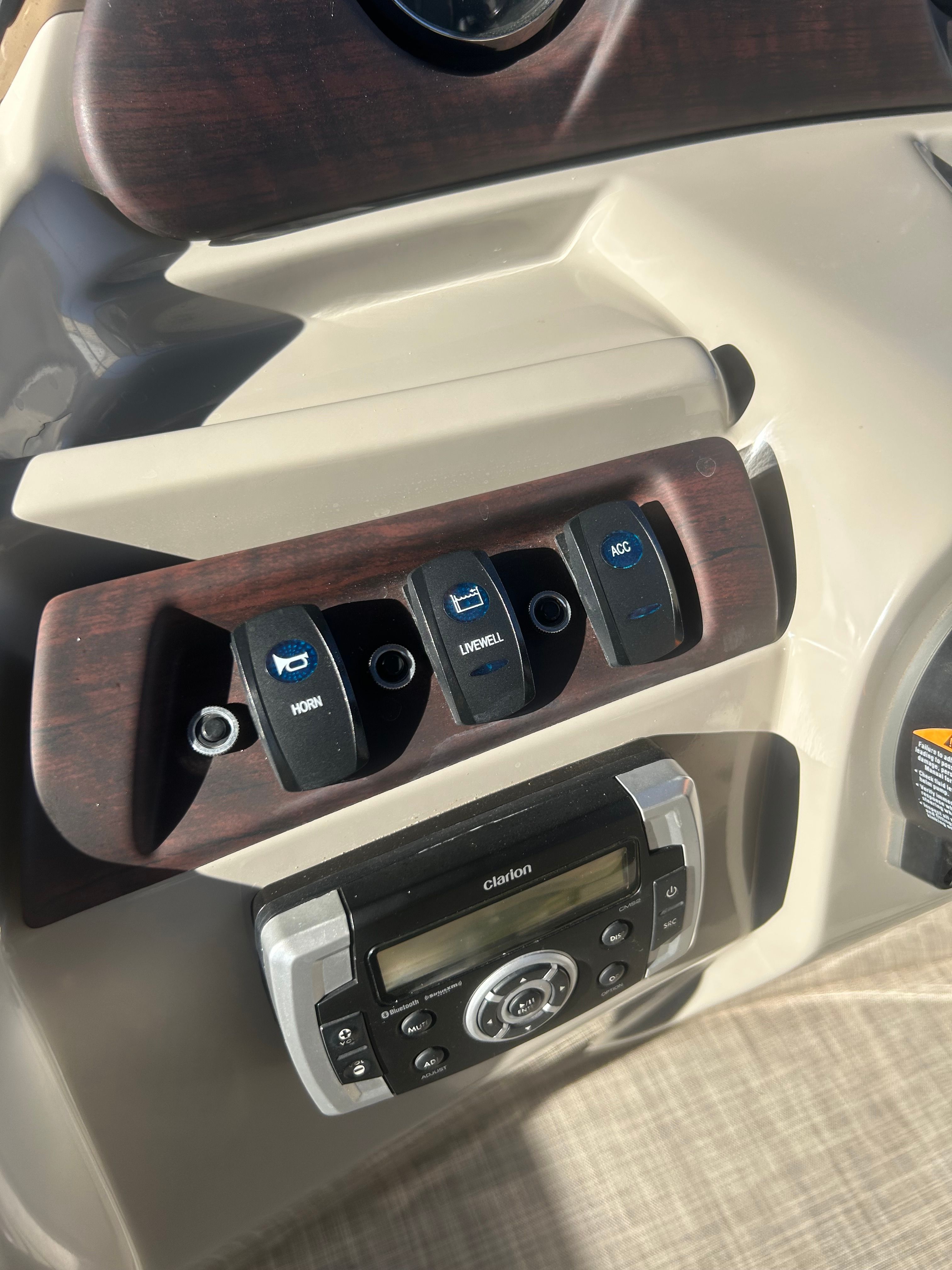 Close-up of a 2018 Berkshire 24RFX CTS helm with various switches and a radio.