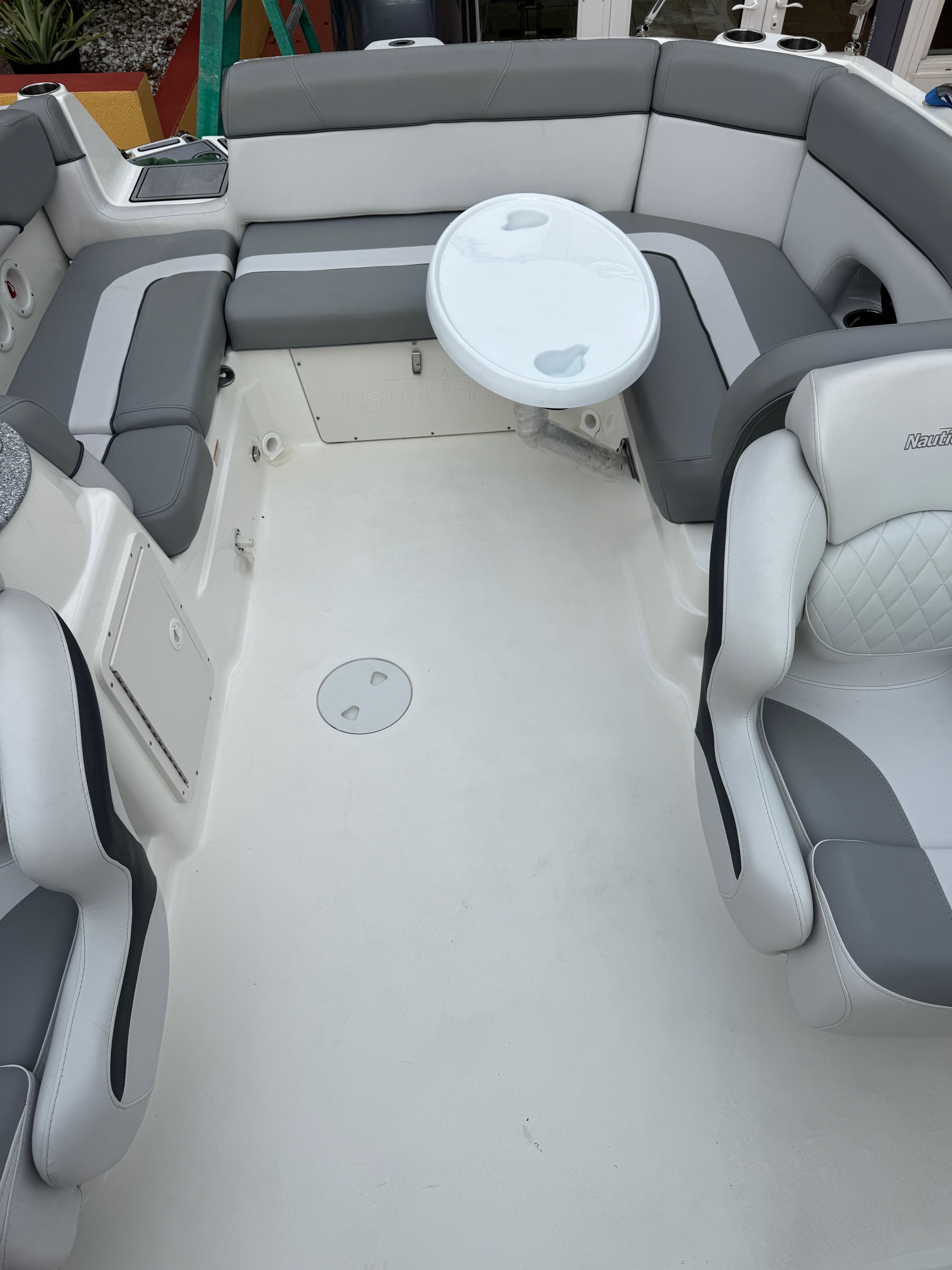 The image shows the cockpit of a 2022 NauticStar 243 DC with gray and white seating.