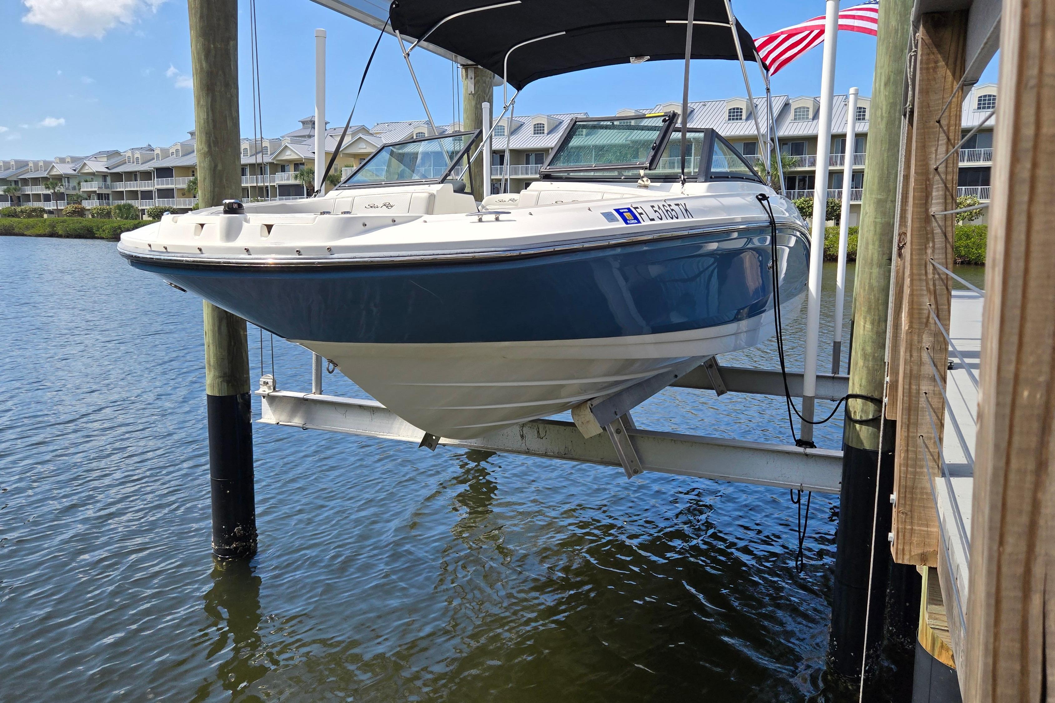 2023 Sea Ray SPX 210 boat on lift, docked by waterfront homes.