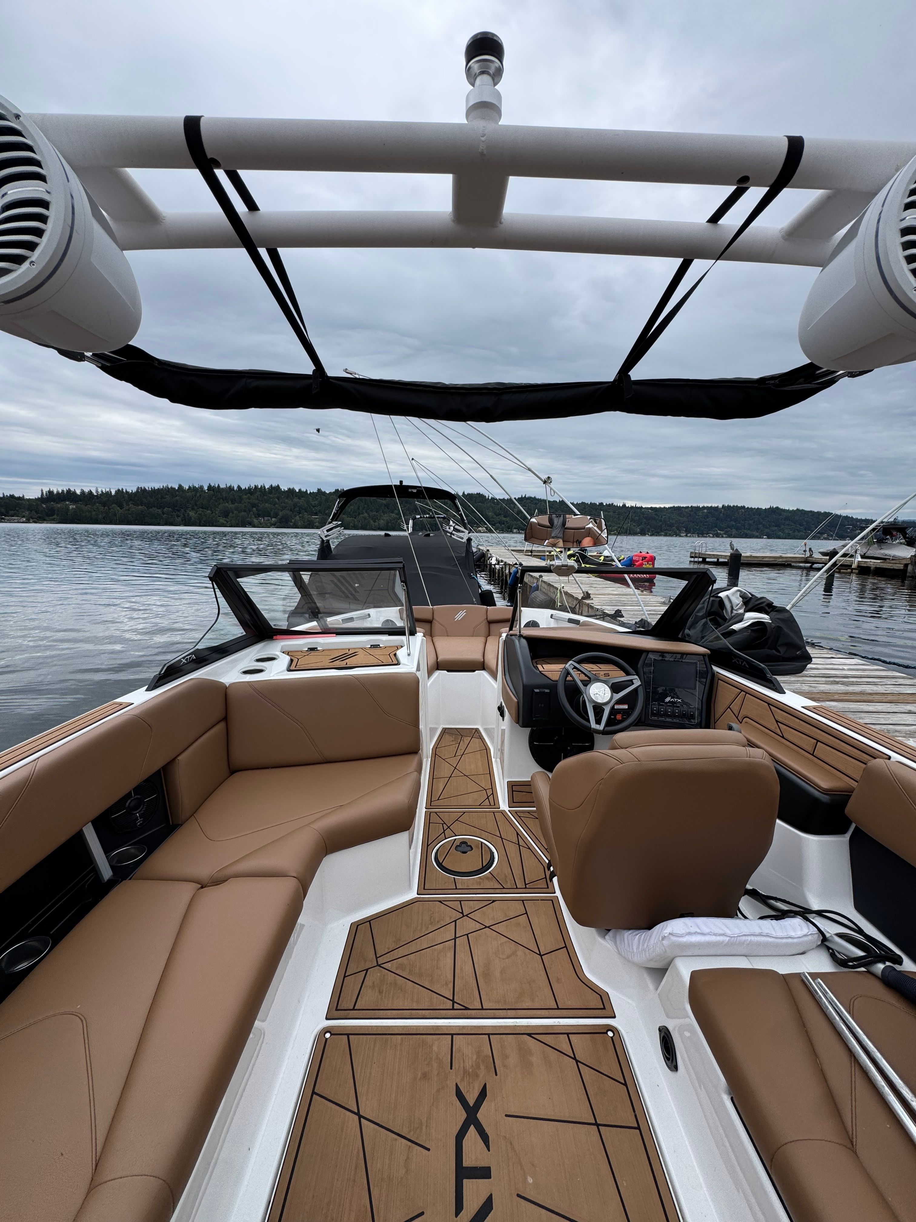 The 2022 ATX Surf Boats 22 Type-S is docked. It features brown seating and a modern design.