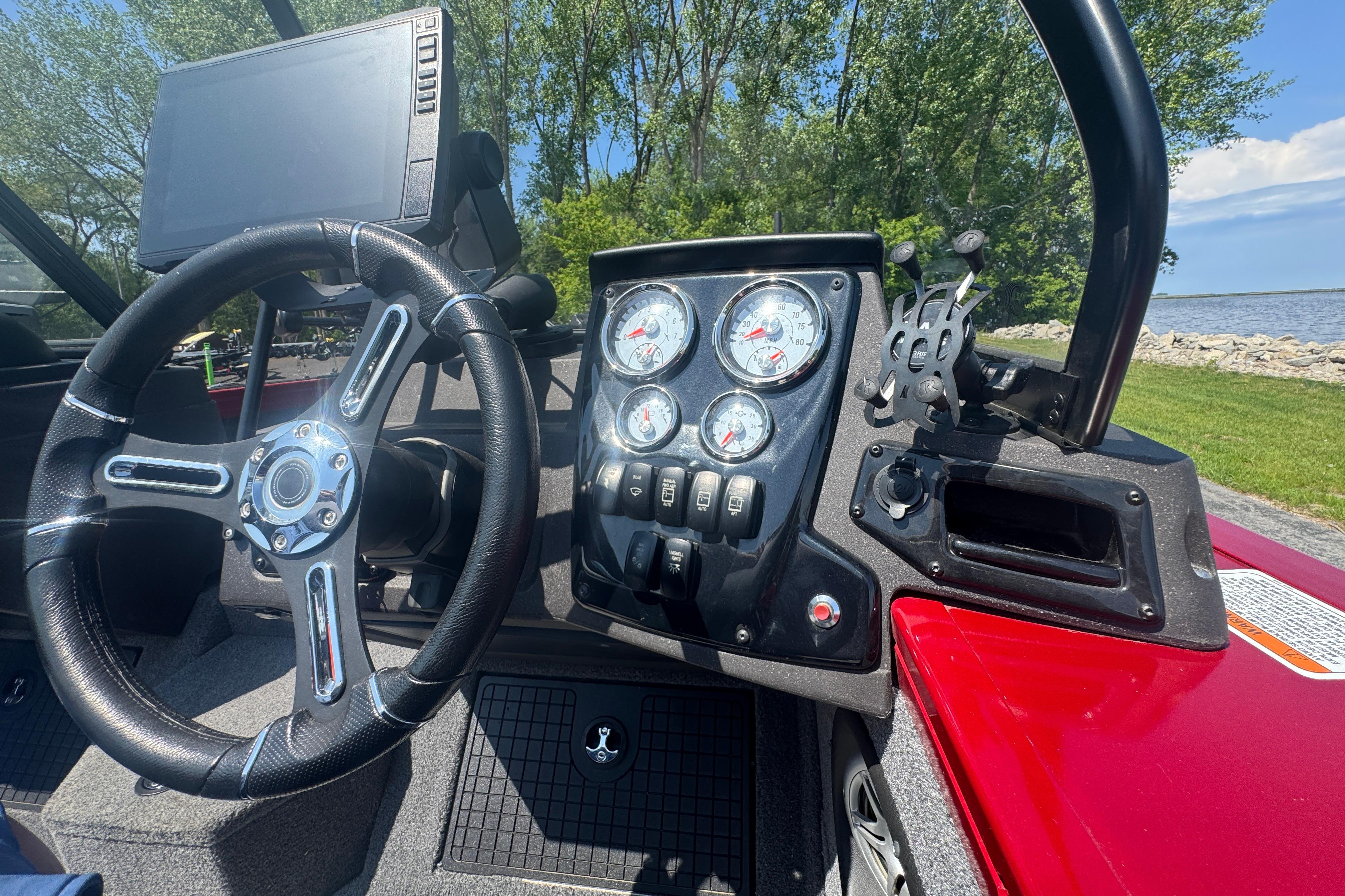 2023 Tracker Targa V-19 Combo dashboard with steering wheel and gauges, near a scenic lake.