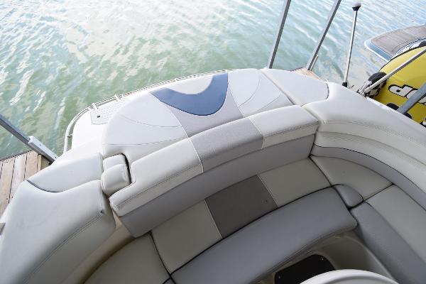The image shows the stern of a boat with cushioned seating and a view of the water.
