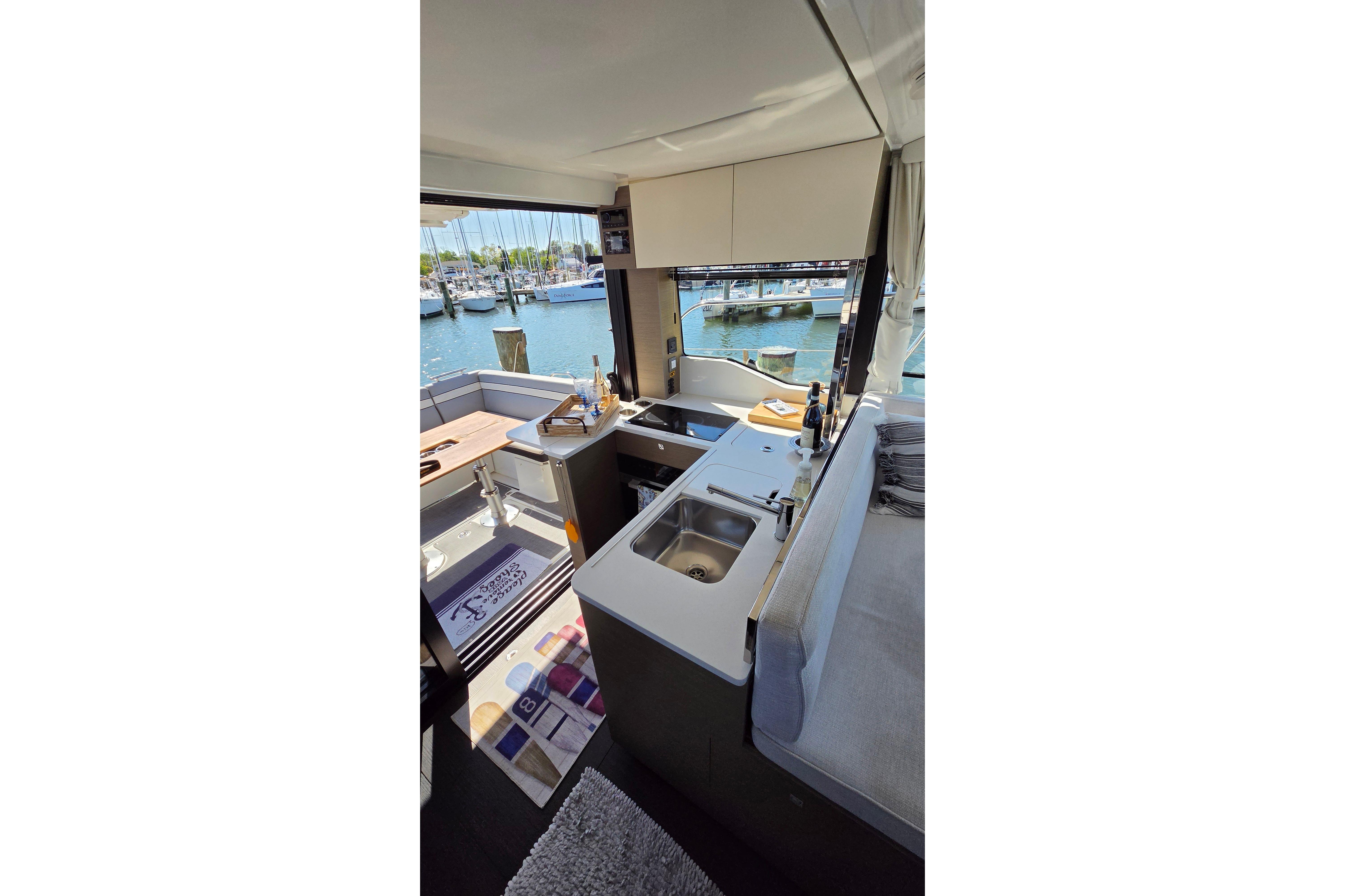 Interior view of 2024 Jeanneau NC Weekender 1295 Fly, featuring a modern kitchen and marina backdrop.