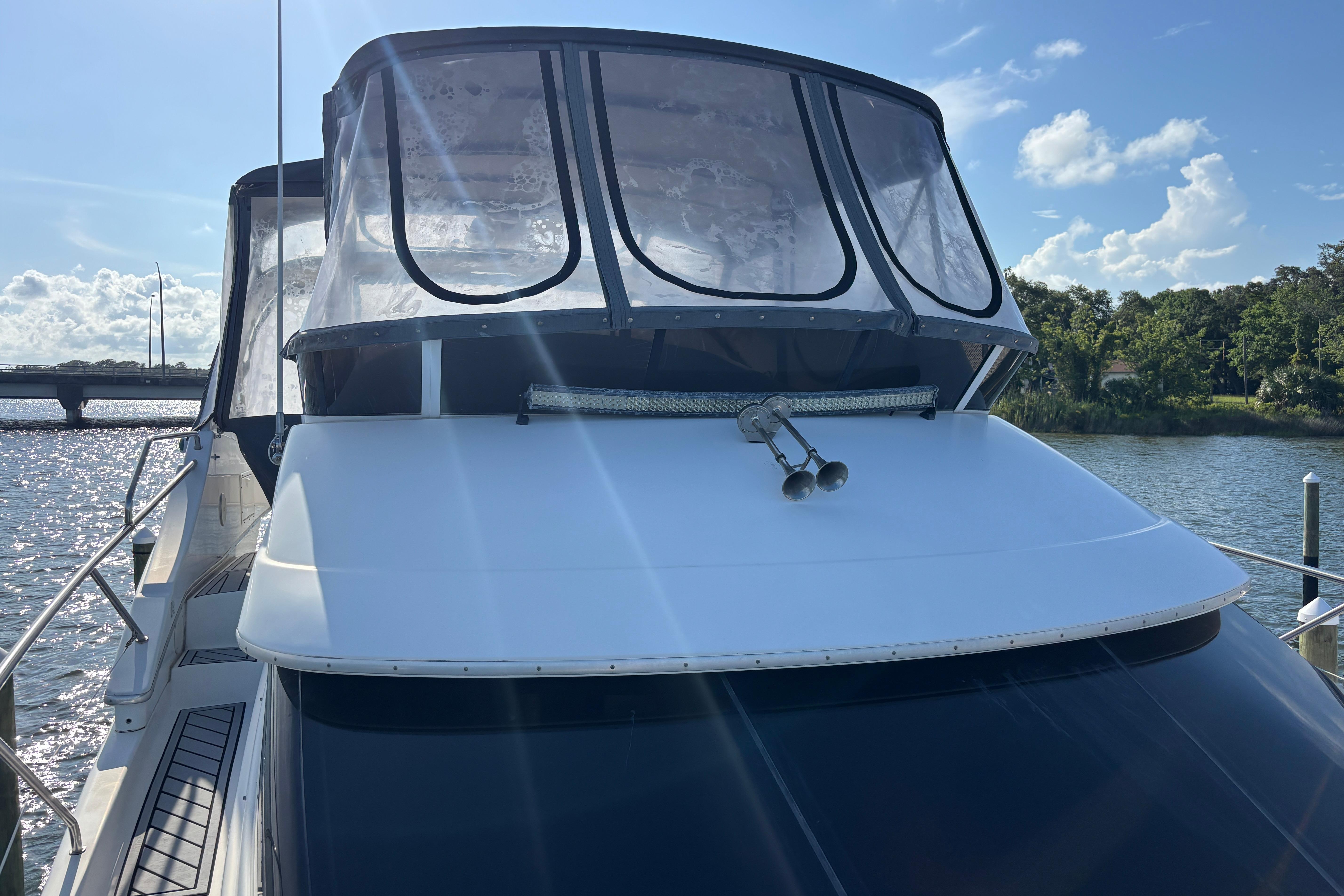 2001 Silverton 410 Sport Bridge yacht docked on a sunny day, featuring sleek design and clear canopy.