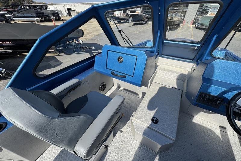 Interior of 2026 SeaArk Dynasty 2.0 boat, featuring blue and gray seating and dashboard.