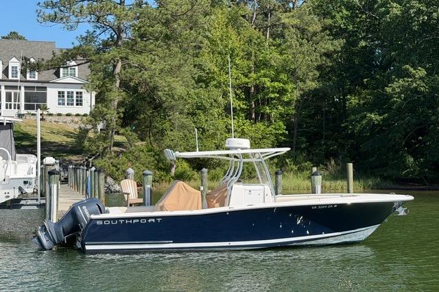 2014 Southport 29 FE boat docked near a lakeside house, surrounded by lush greenery.