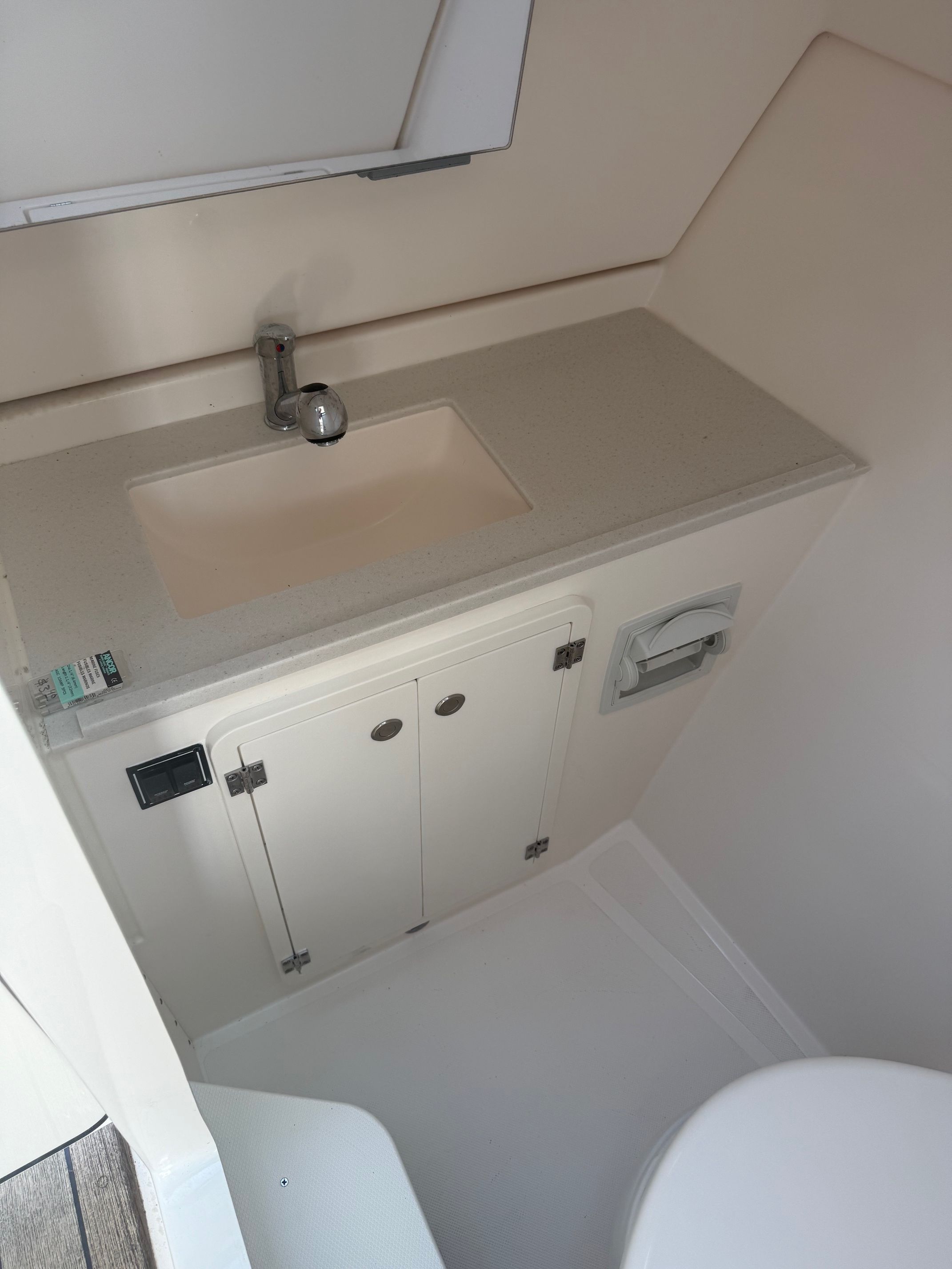 The image shows a clean, modern boat bathroom with a sink and cabinet.