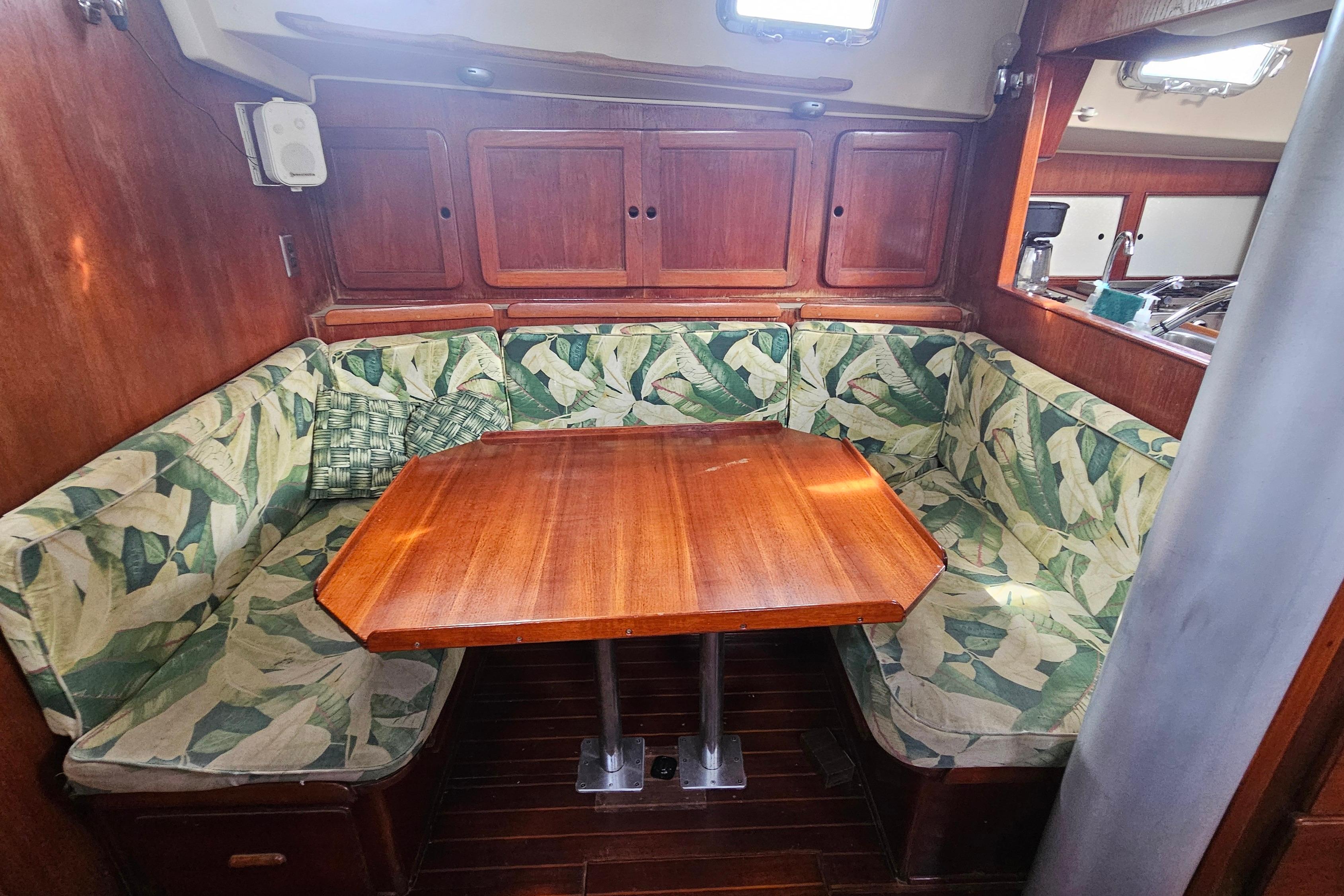 Cozy dining area in a 1982 Morgan 462 yacht with wooden table and leaf-patterned cushions.