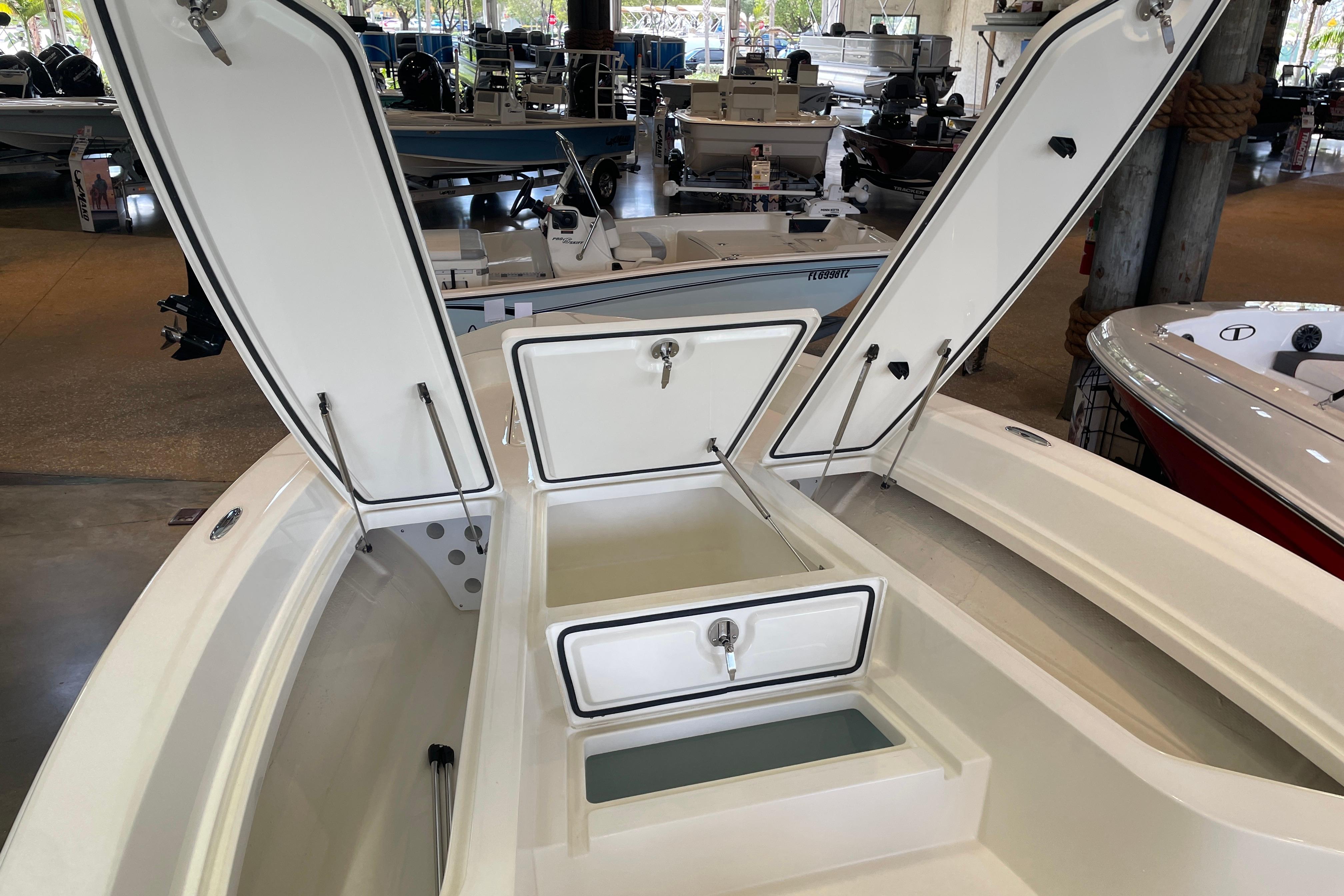2026 Mako 24 APEX boat with open storage compartments in a showroom.