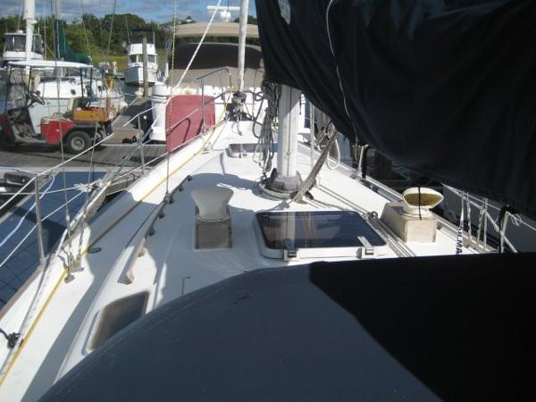 Deck of a sailboat in a harbor with masts and ropes.
