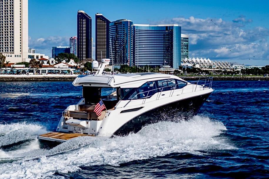 2017 Sea Ray 460 Sundancer yacht cruising near city skyline on a sunny day.