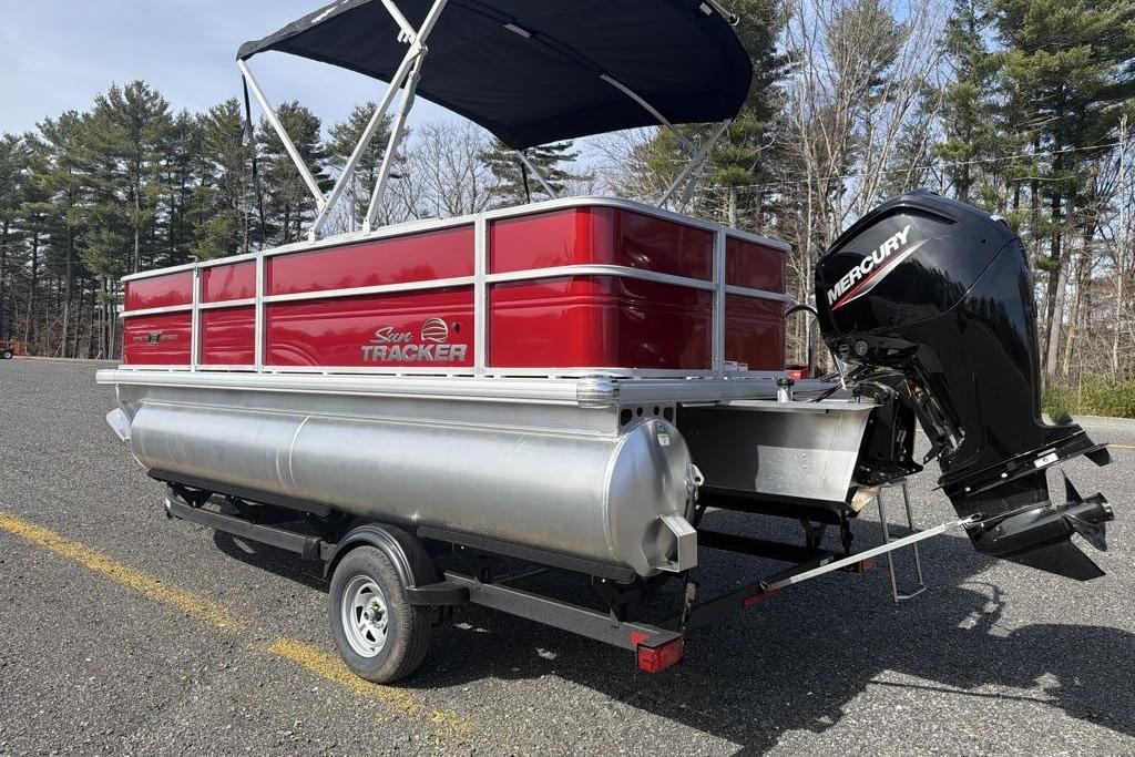 2026 Sun Tracker Party Barge 18 DLX pontoon boat with Mercury outboard motor in a parking lot.