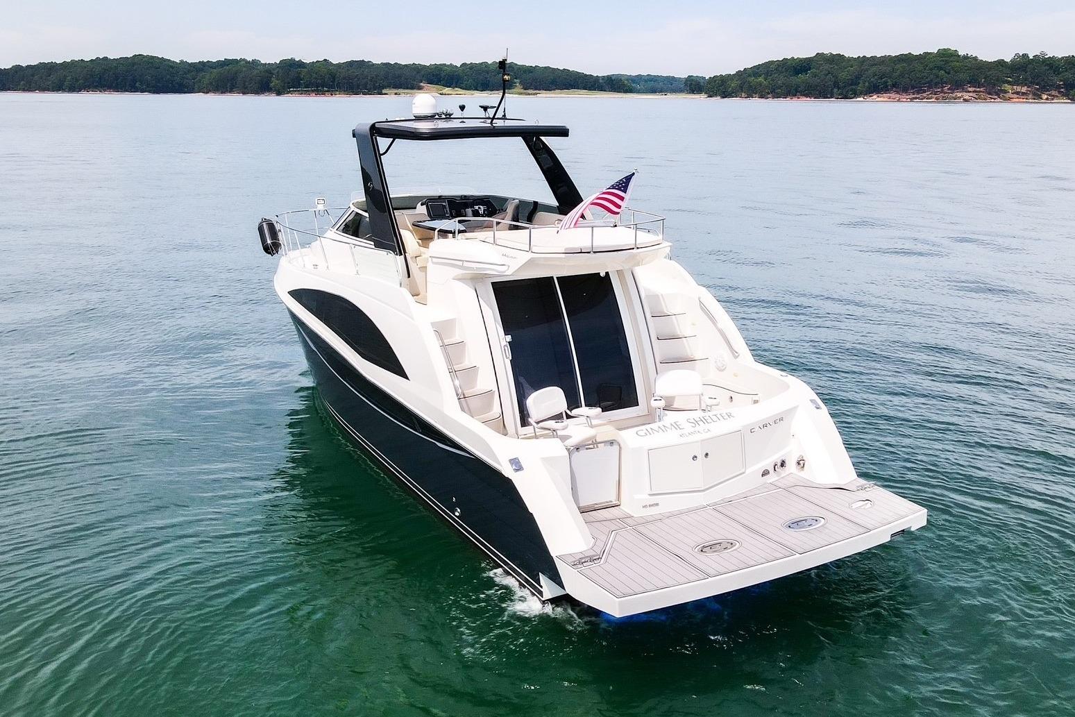 2011 Carver 44 Sojourn yacht cruising on a serene lake with lush green shoreline.