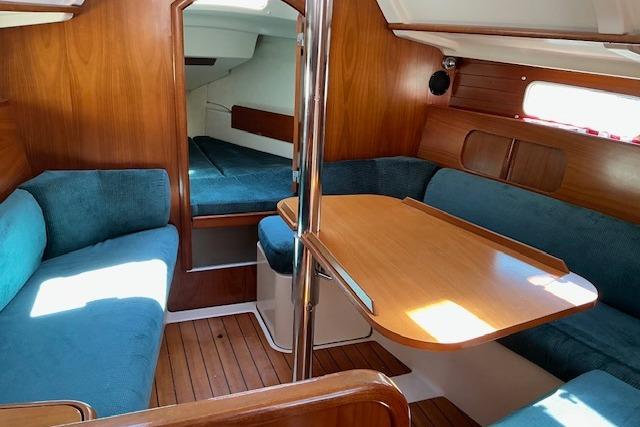 Interior of 2000 Beneteau Oceanis 321 sailboat with wooden finish and blue seating.