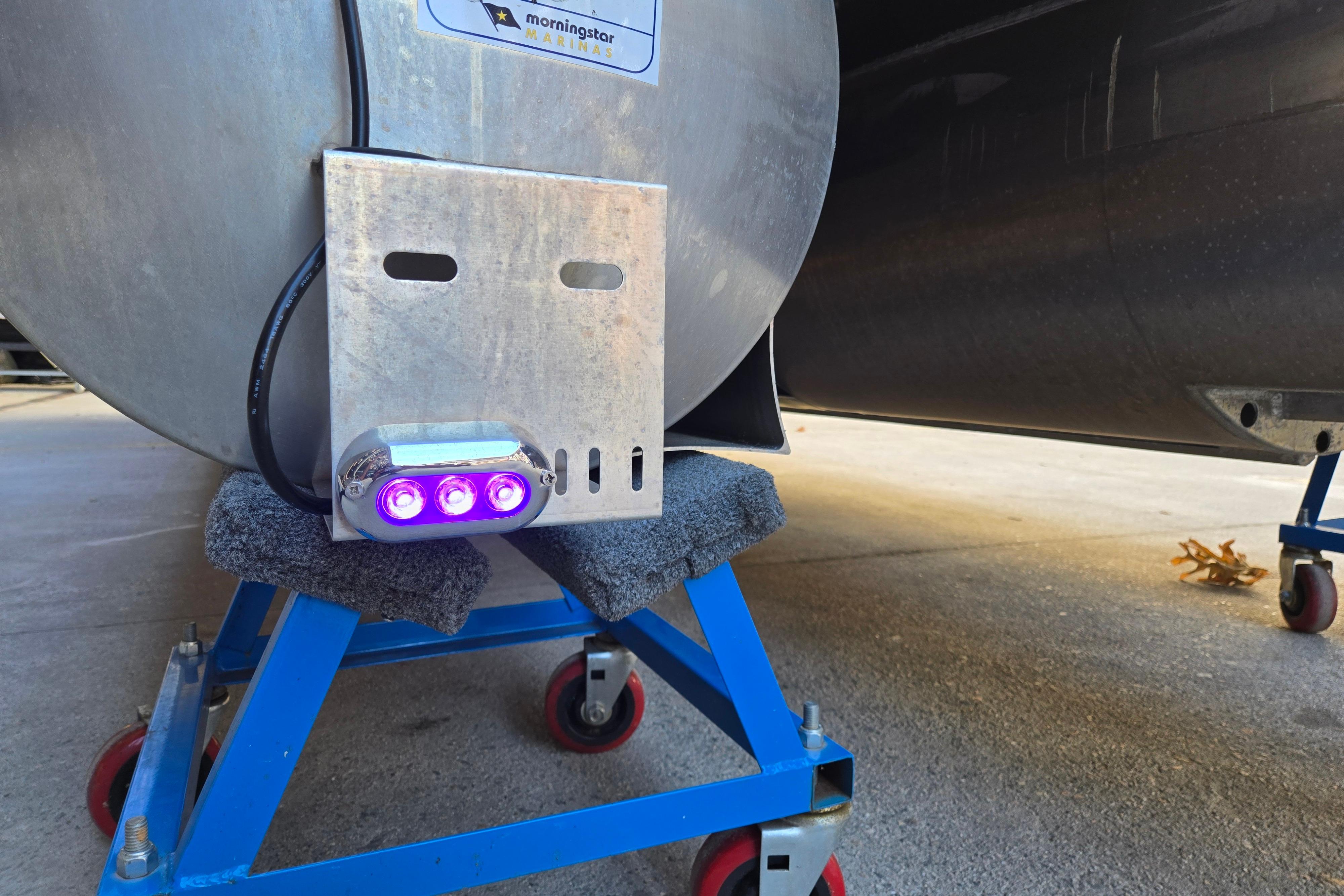 2024 Godfrey Sweetwater 2486 SB pontoon with purple LED lights on a blue stand.
