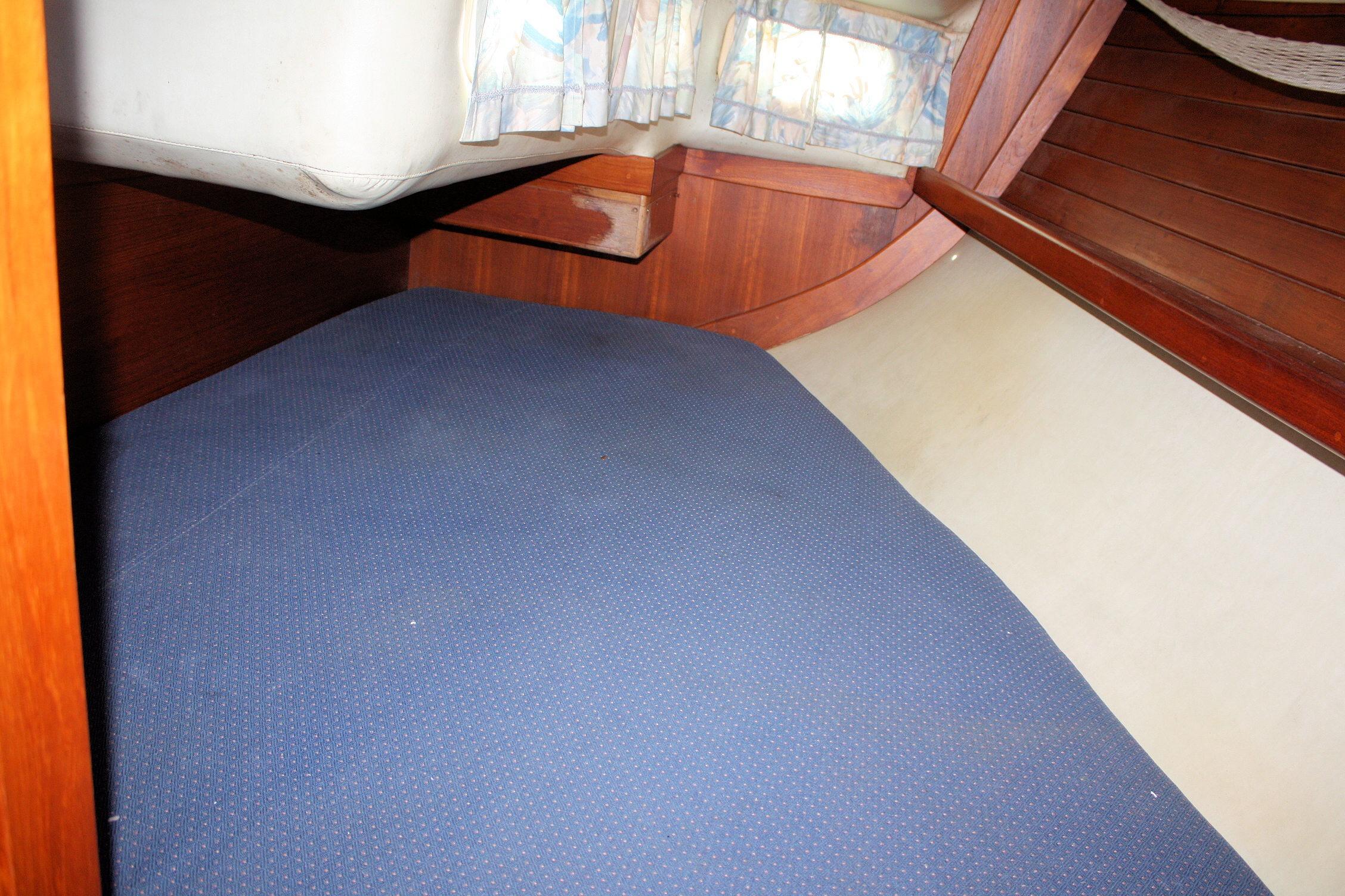 Interior cabin of 1987 Ericson 38-200 sailboat with blue bedding and wooden accents.
