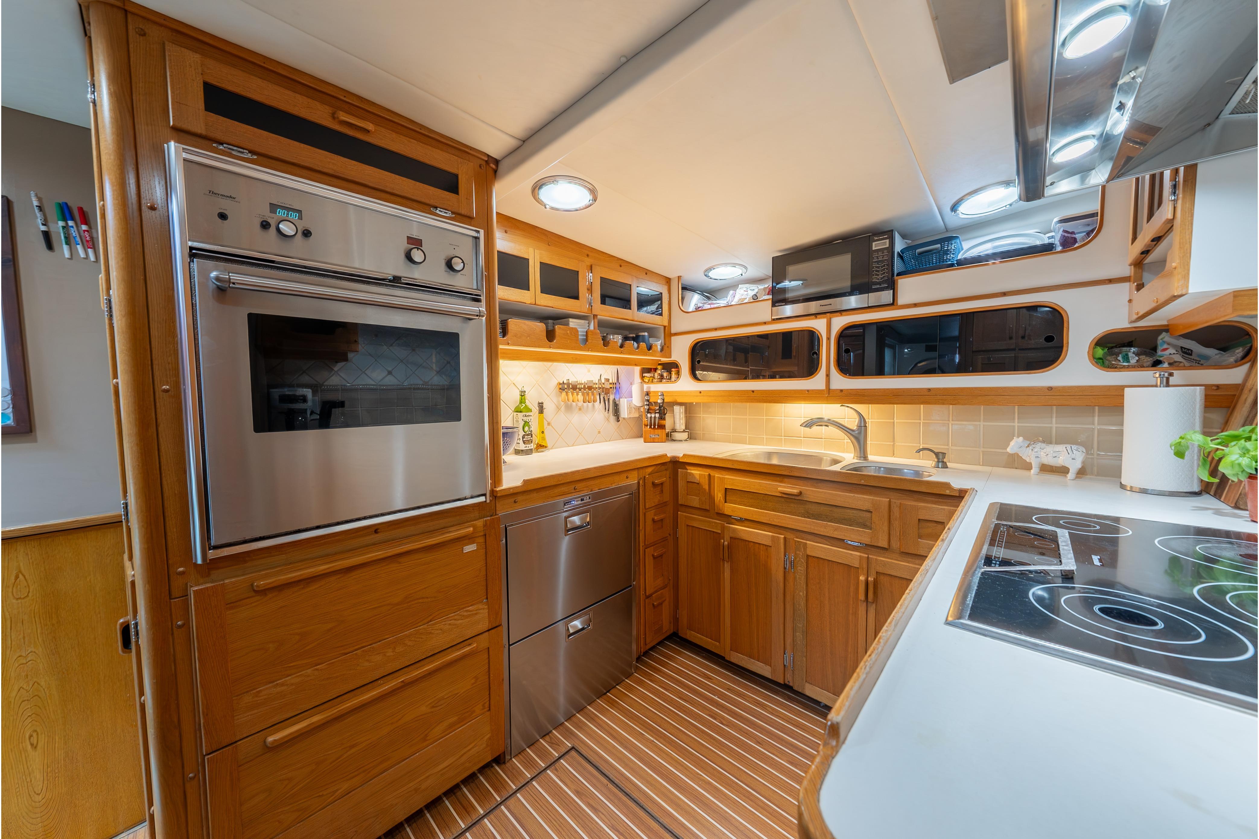 1963 Trumpy Classic yacht kitchen with wood cabinetry, modern appliances, and sleek countertops.