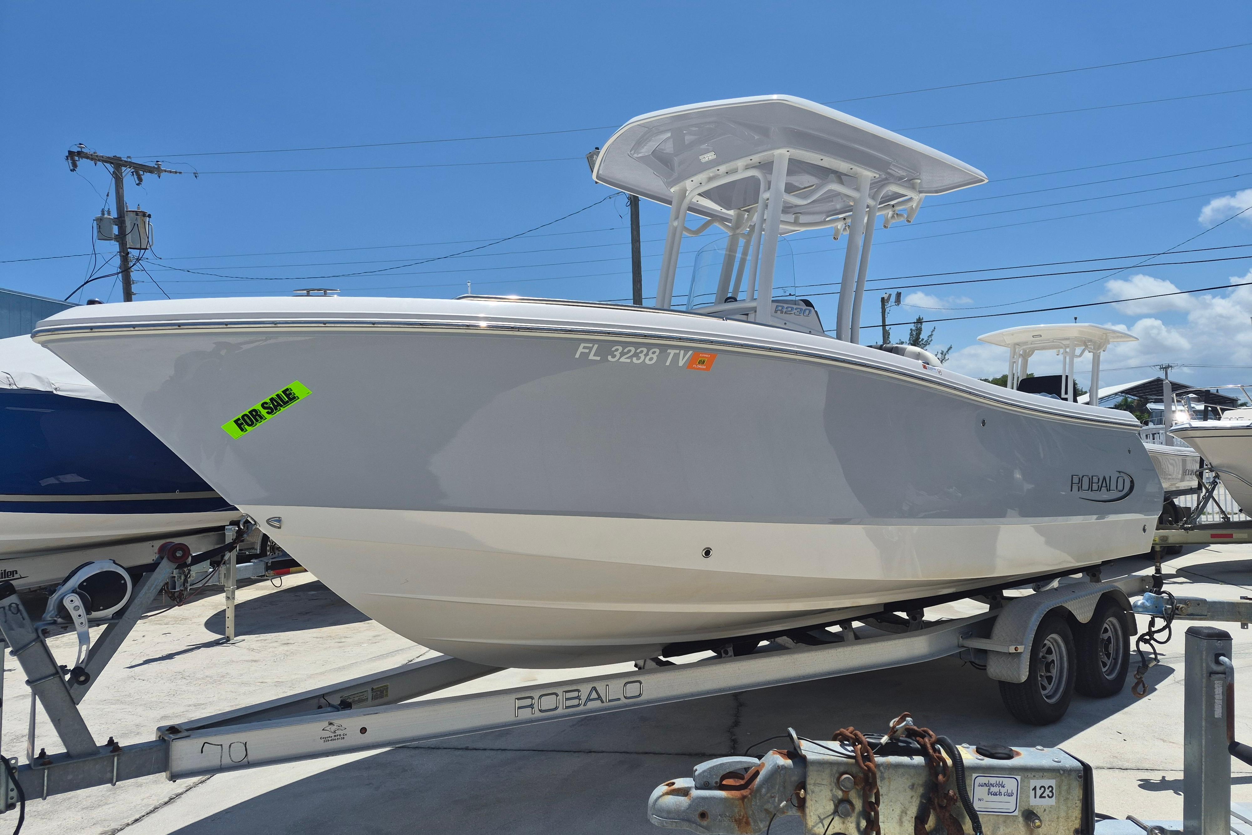 2023 Robalo R230 Center Console boat on trailer, for sale under clear blue sky.