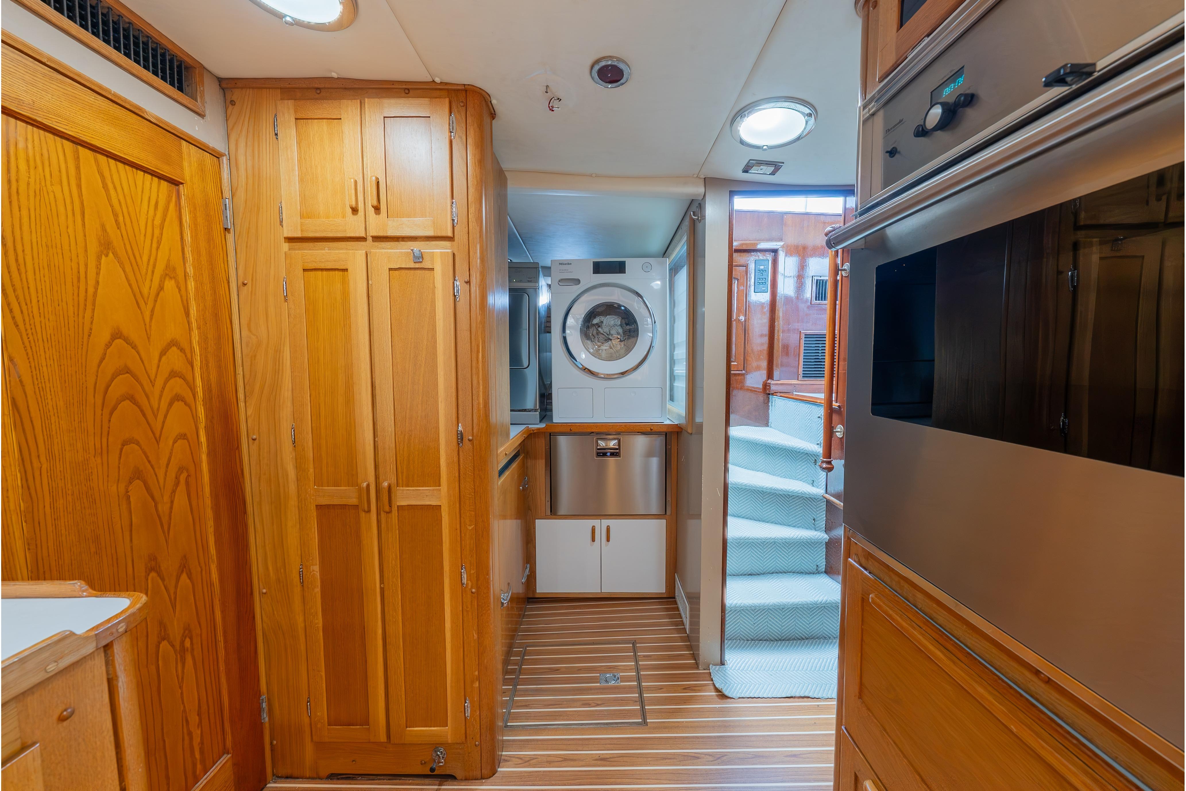 Laundry area in a 1963 Trumpy Classic yacht with wooden cabinetry and modern appliances.